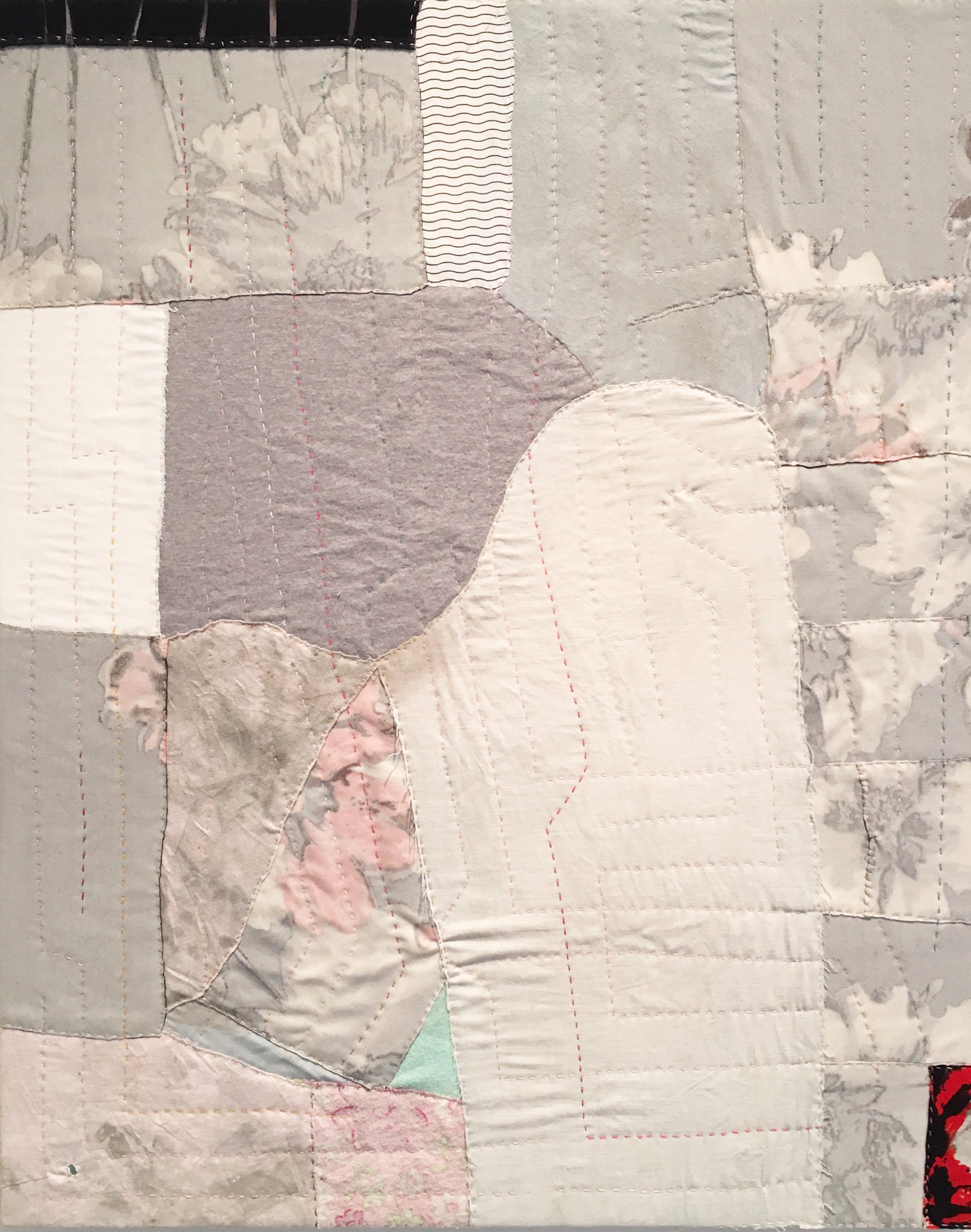 A close up of a quilted wall hanging on a wall.