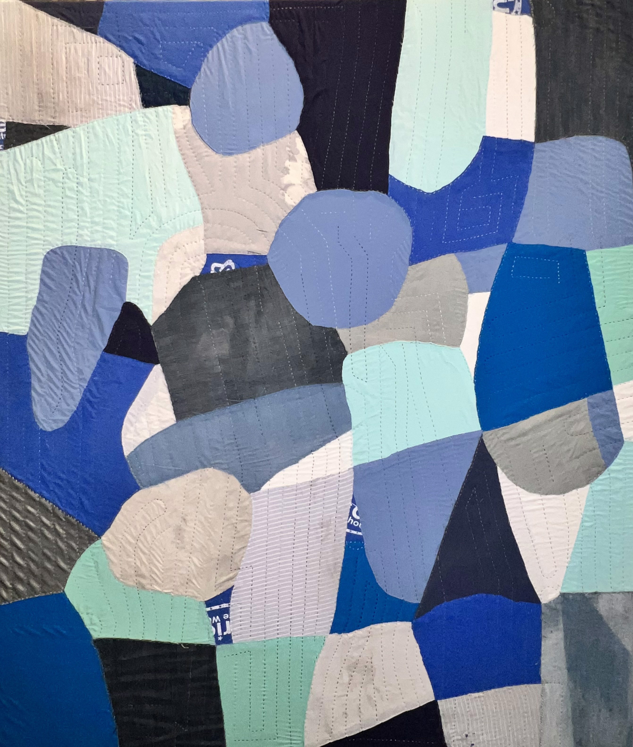 A blue and black quilt on a white wall.