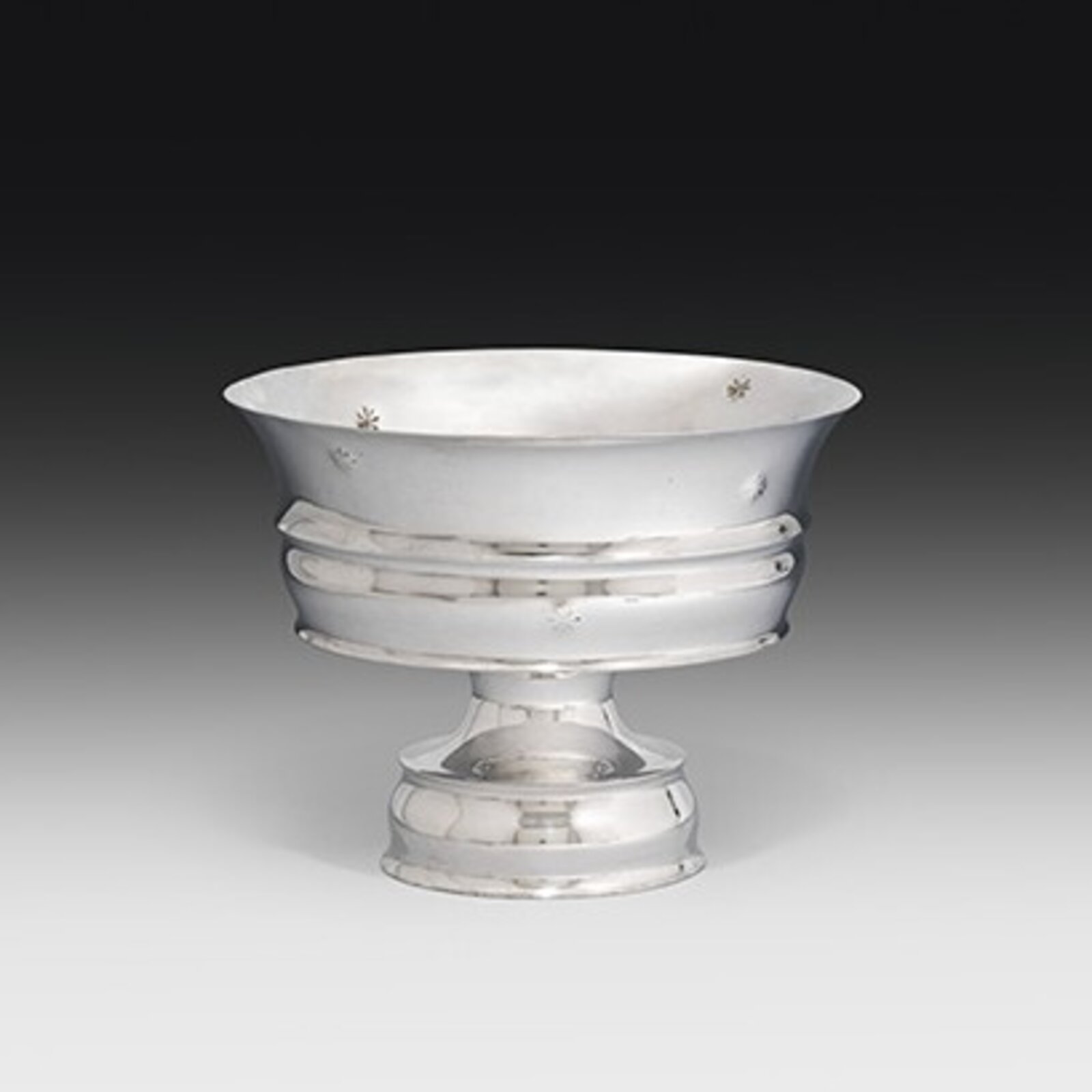 A polished silver bowl with a pedestal base and delicate floral marks.