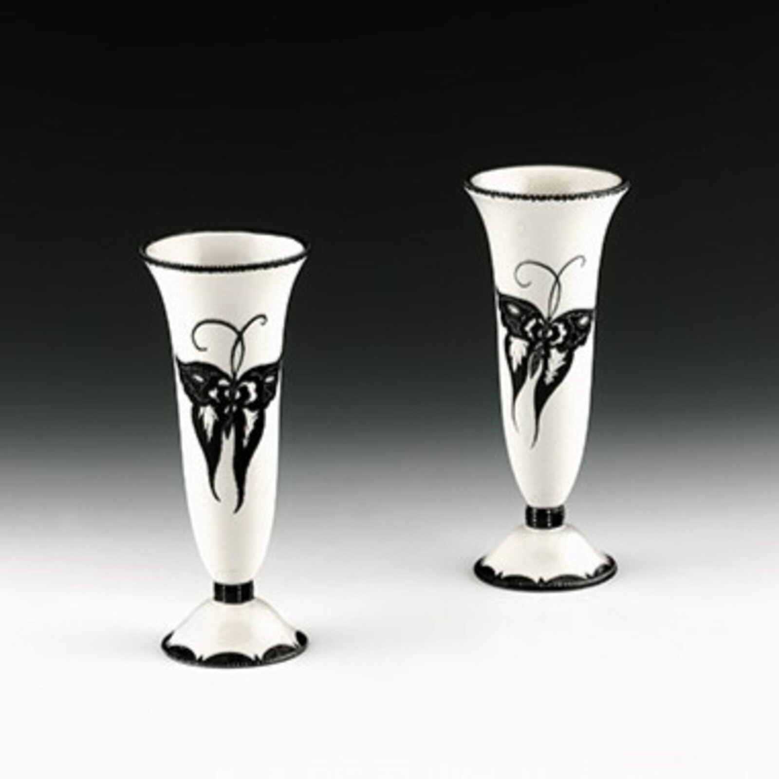A pair of white ceramic vases featuring black butterfly motifs and scalloped edges.