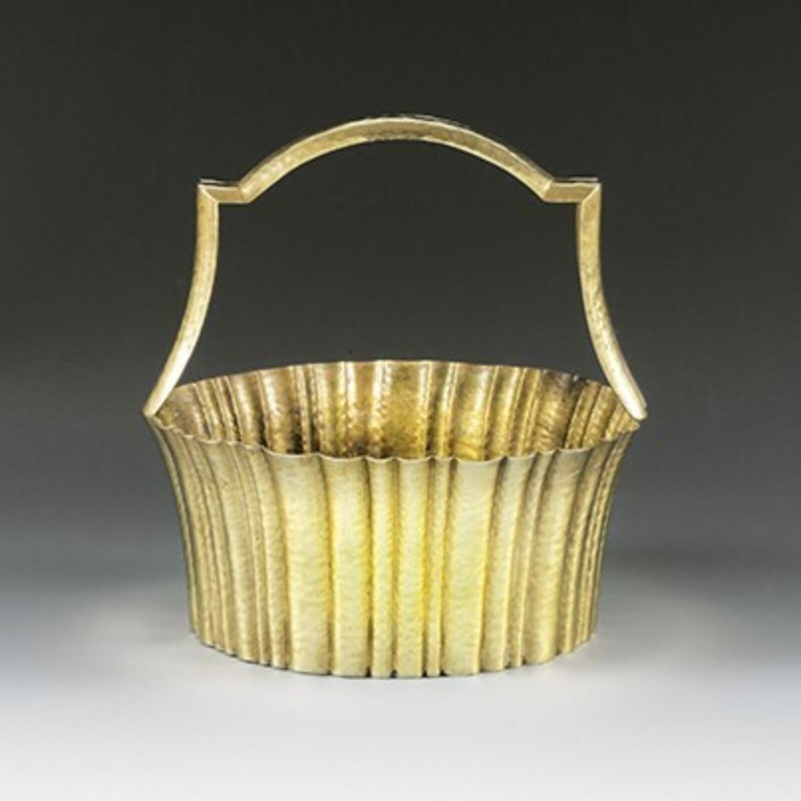 A golden metal basket with a fluted body and arched handle.