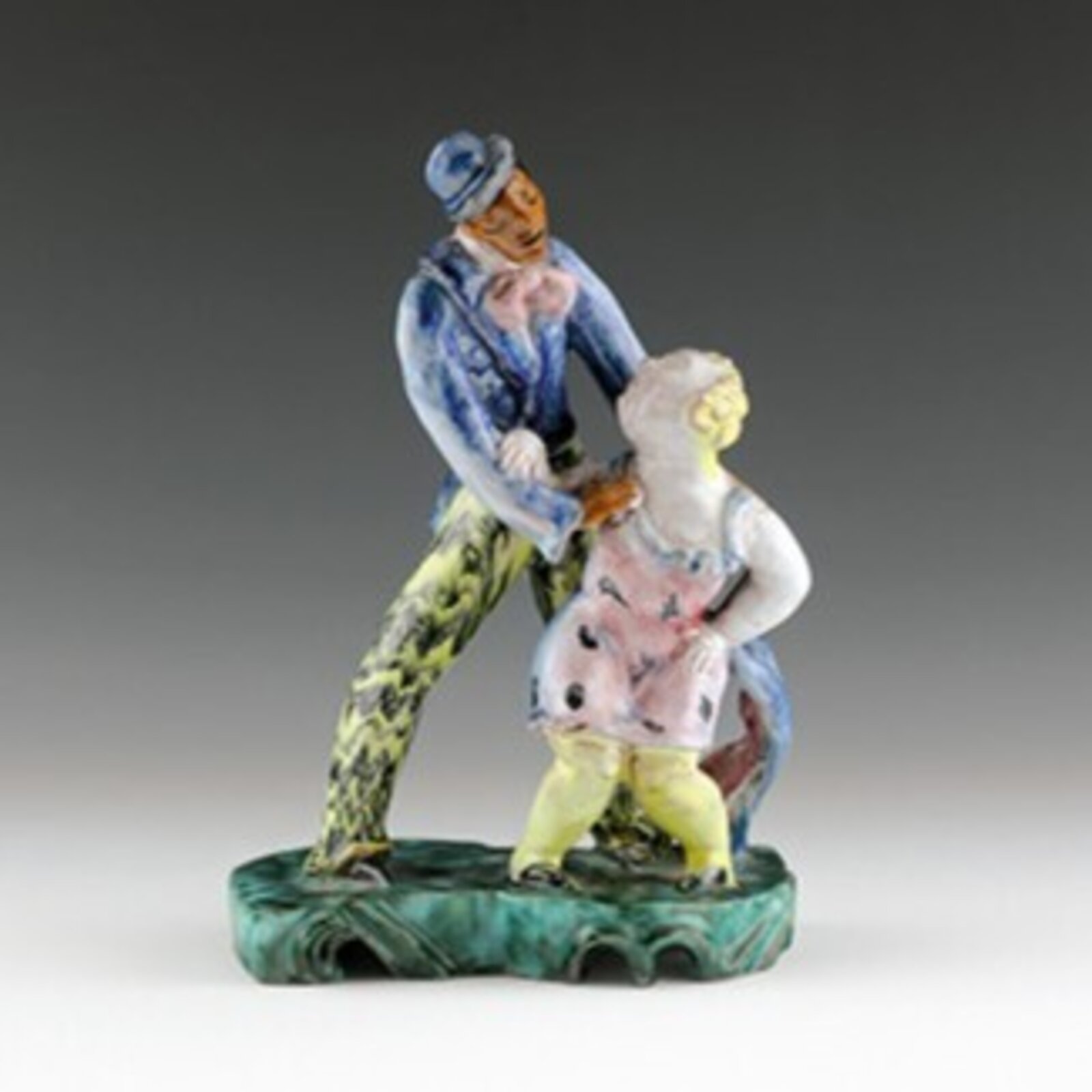 A colorful porcelain figurine of a dancing couple on an ornate base.