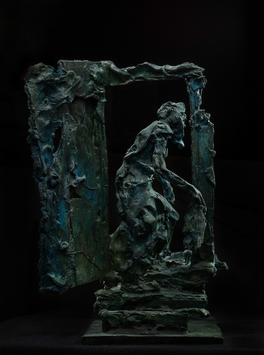 A bronze sculpture of a figure emerging from a broken frame.