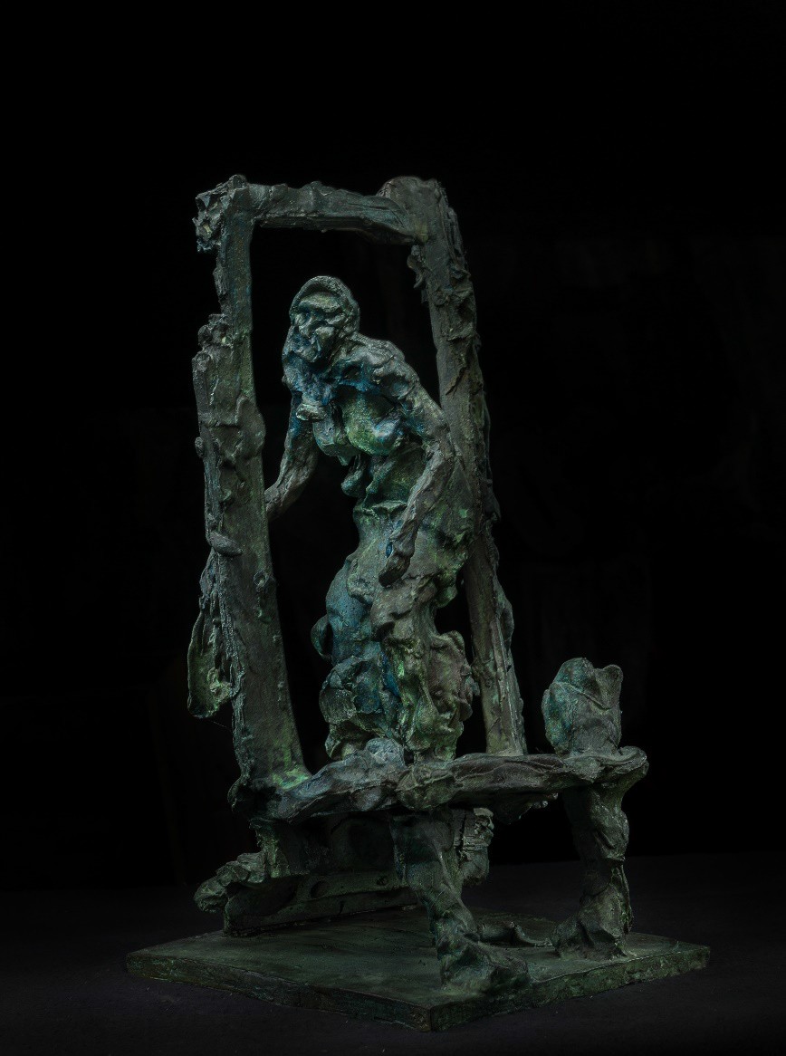 A bronze sculpture of a figure emerging from a broken frame.