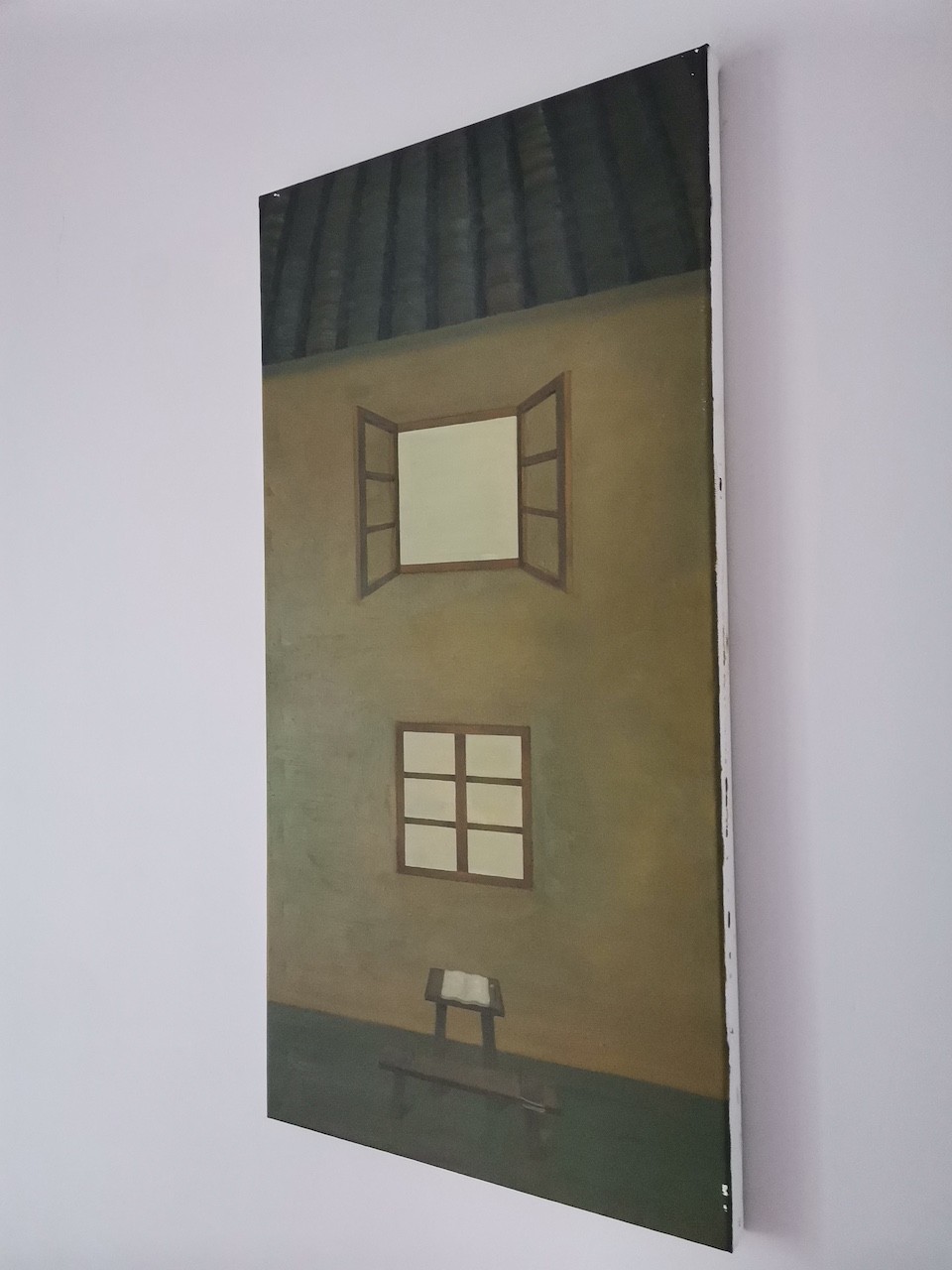 A quiet interior scene featuring a small table with an open book, set against a wall with two windows.