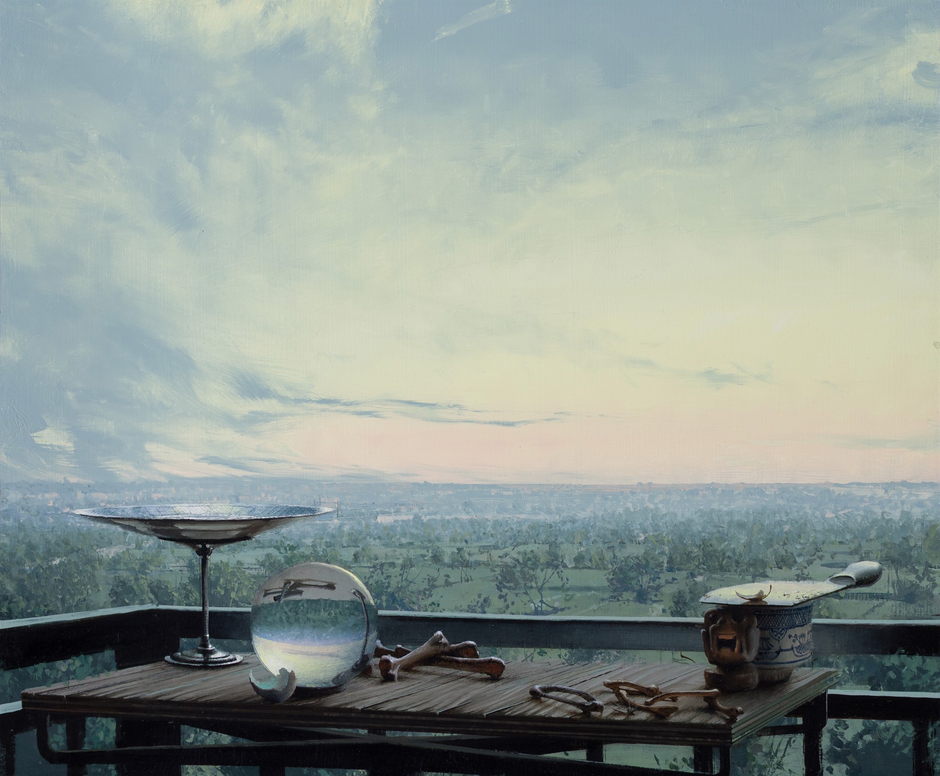A still life arrangement of eclectic objects on a wooden table overlooking a vast, hazy landscape.
