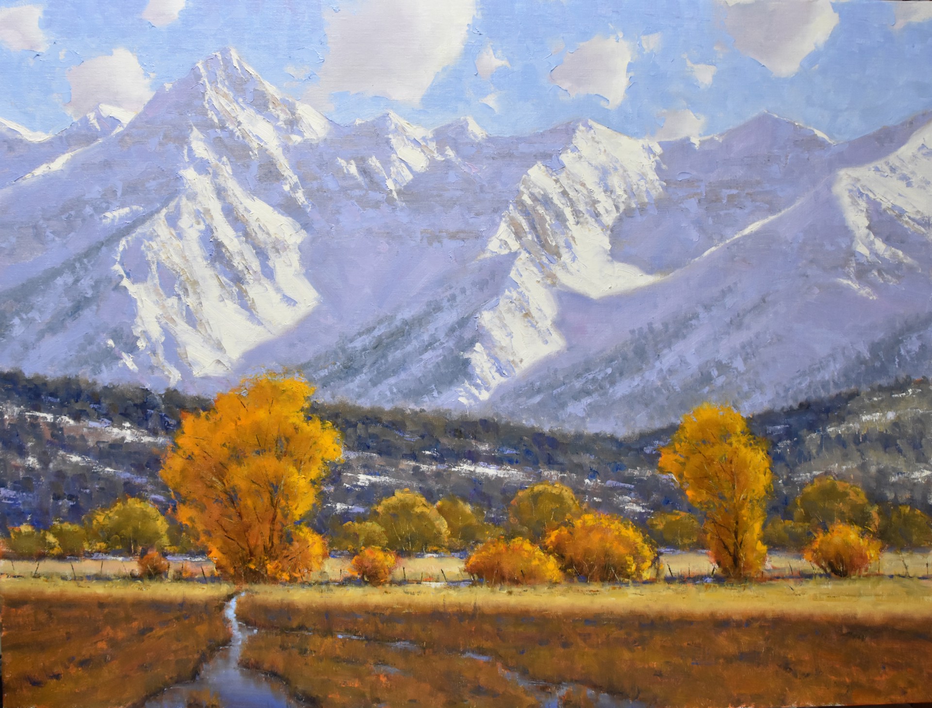 A landscape painting of a valley with golden autumn trees and towering snow-capped mountains.