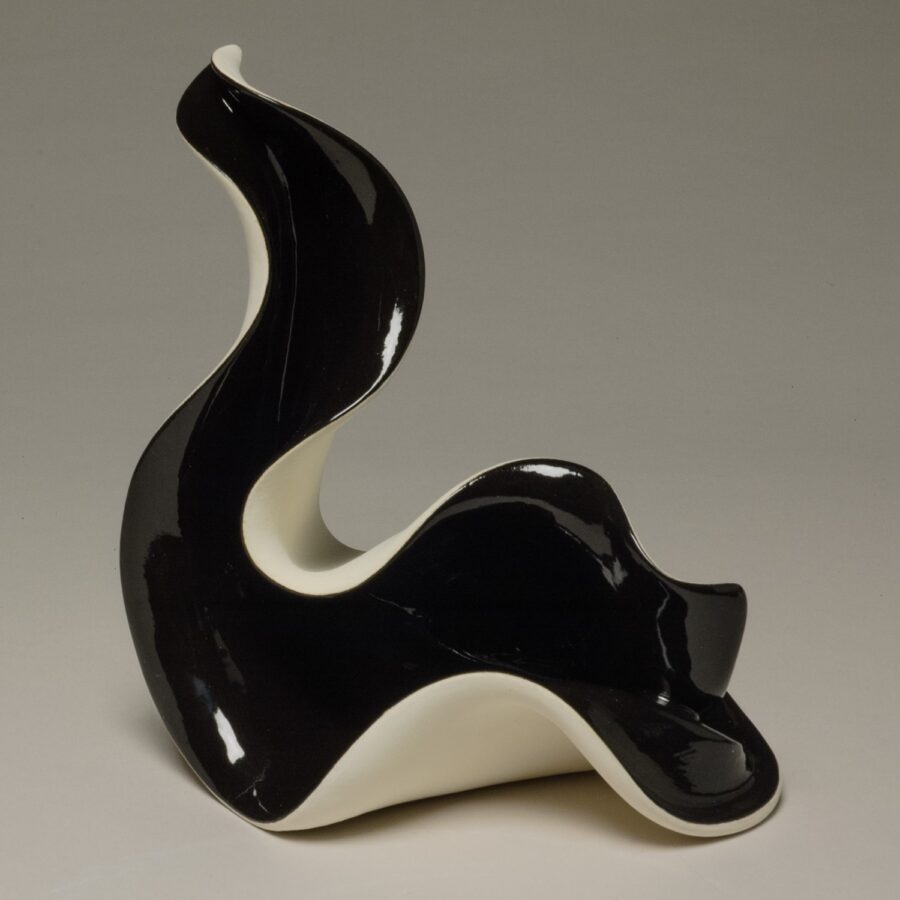 A glossy black and white ceramic sculpture with a fluid, wave-like form.