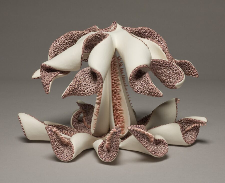 A sculptural ceramic piece resembling a blooming flower with textured, organic tendrils.