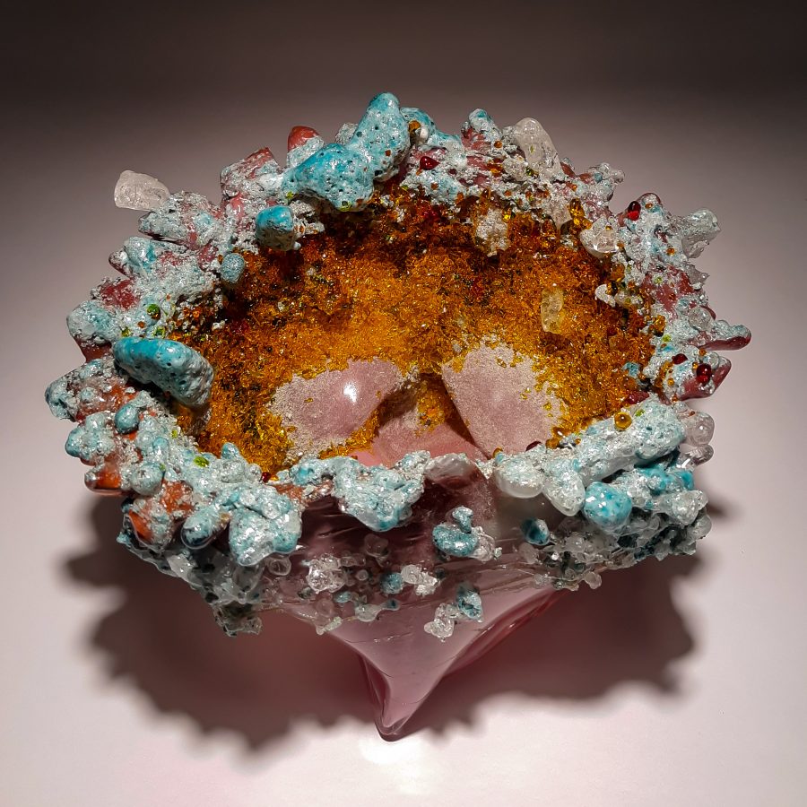 A colorful glass sculpture resembling a coral reef with a hollow center.