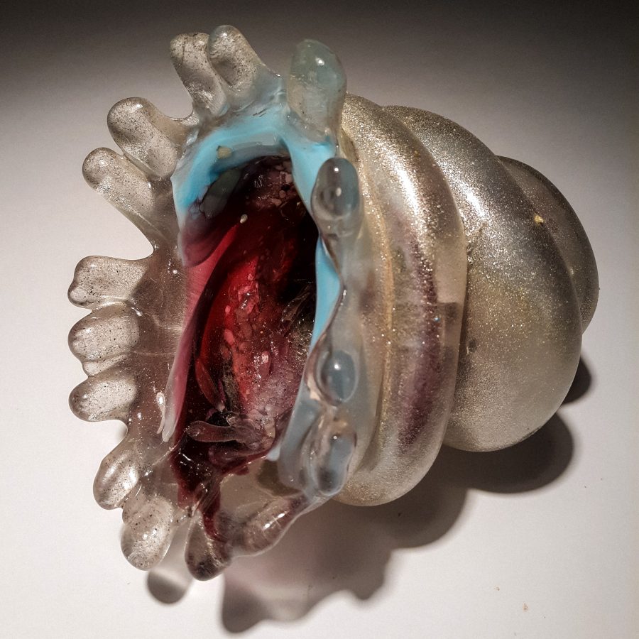 A translucent glass sculpture shaped like an open clam shell with a glowing red interior.