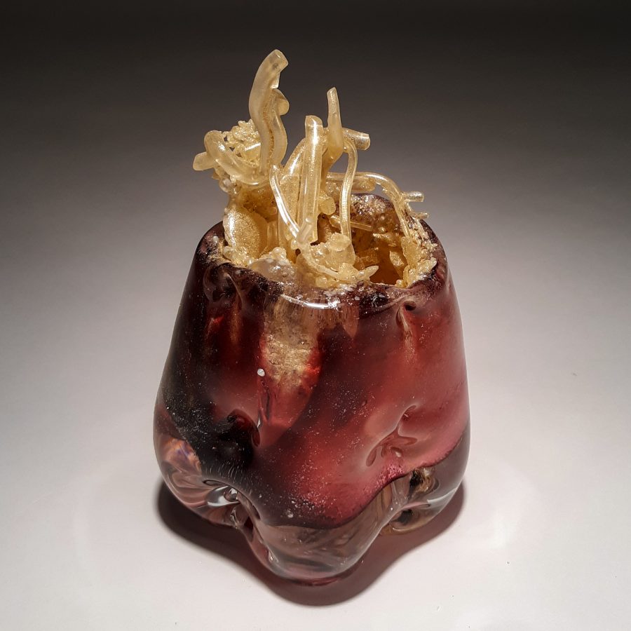 A glass sculpture of a reddish-brown vessel with translucent, organic tendrils emerging from its top.