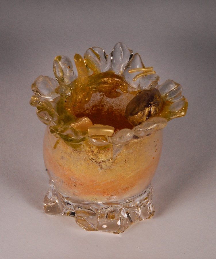 A translucent glass vessel with a flower-shaped rim and amber interior.
