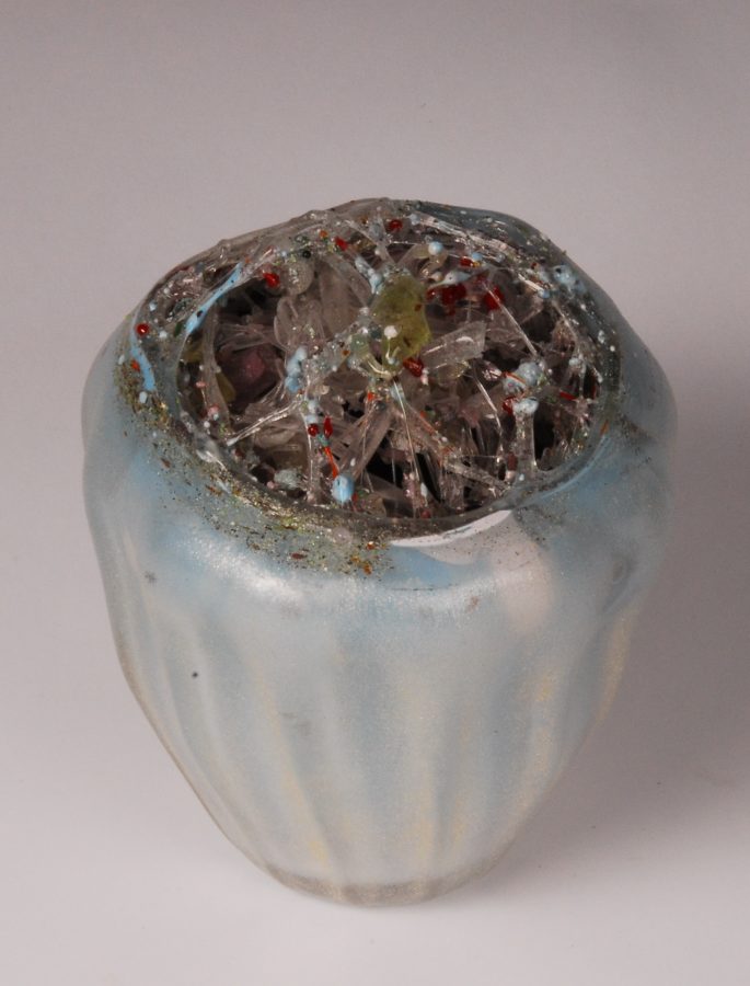 A translucent ceramic vessel with a cracked, crystalline top against a neutral background.
