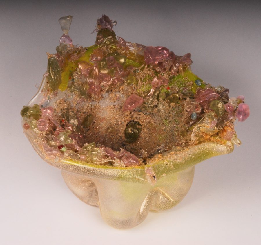 A sculptural glass bowl with a rough, organic surface and embedded colorful crystals.