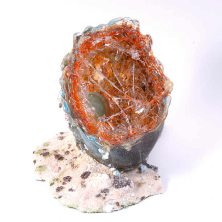 A sculptural piece resembling a cracked egg with vibrant orange filaments and translucent strands.