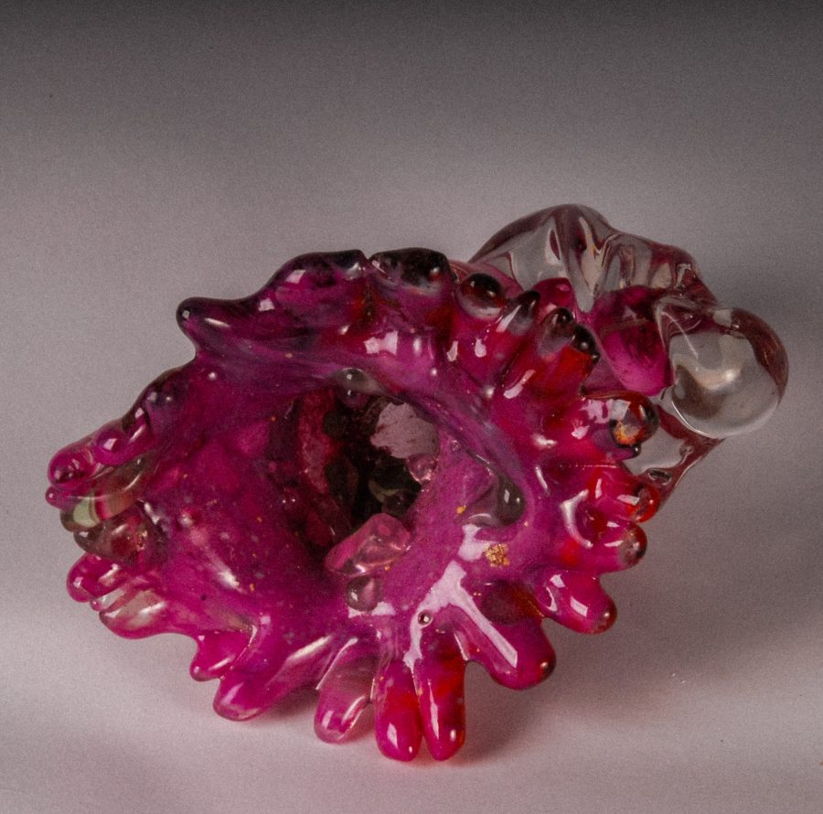 A translucent magenta glass sculpture with organic, coral-like forms and a clear bubble.