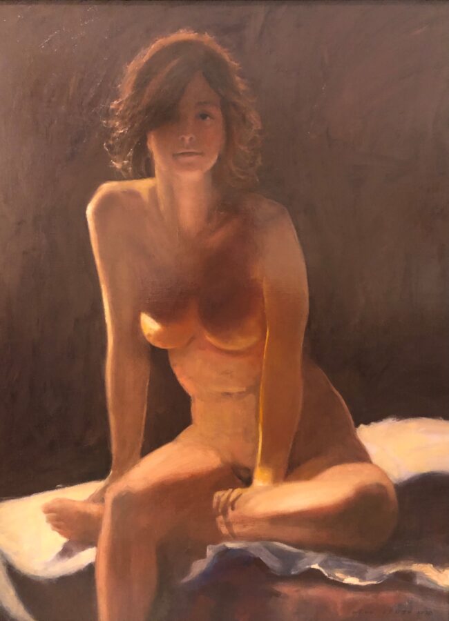 A nude figure sits in a contemplative pose, illuminated by warm light against a dark background.