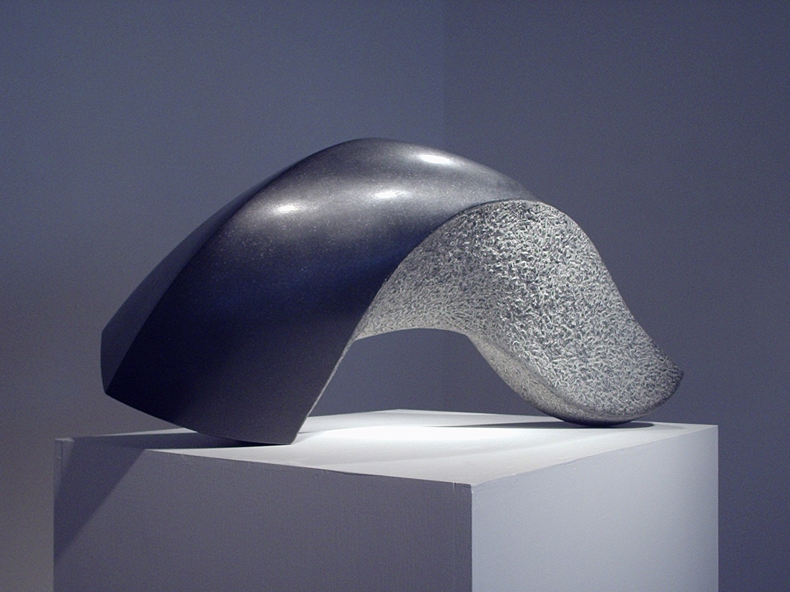 A sculpture on a white pedestal in a dark room.
