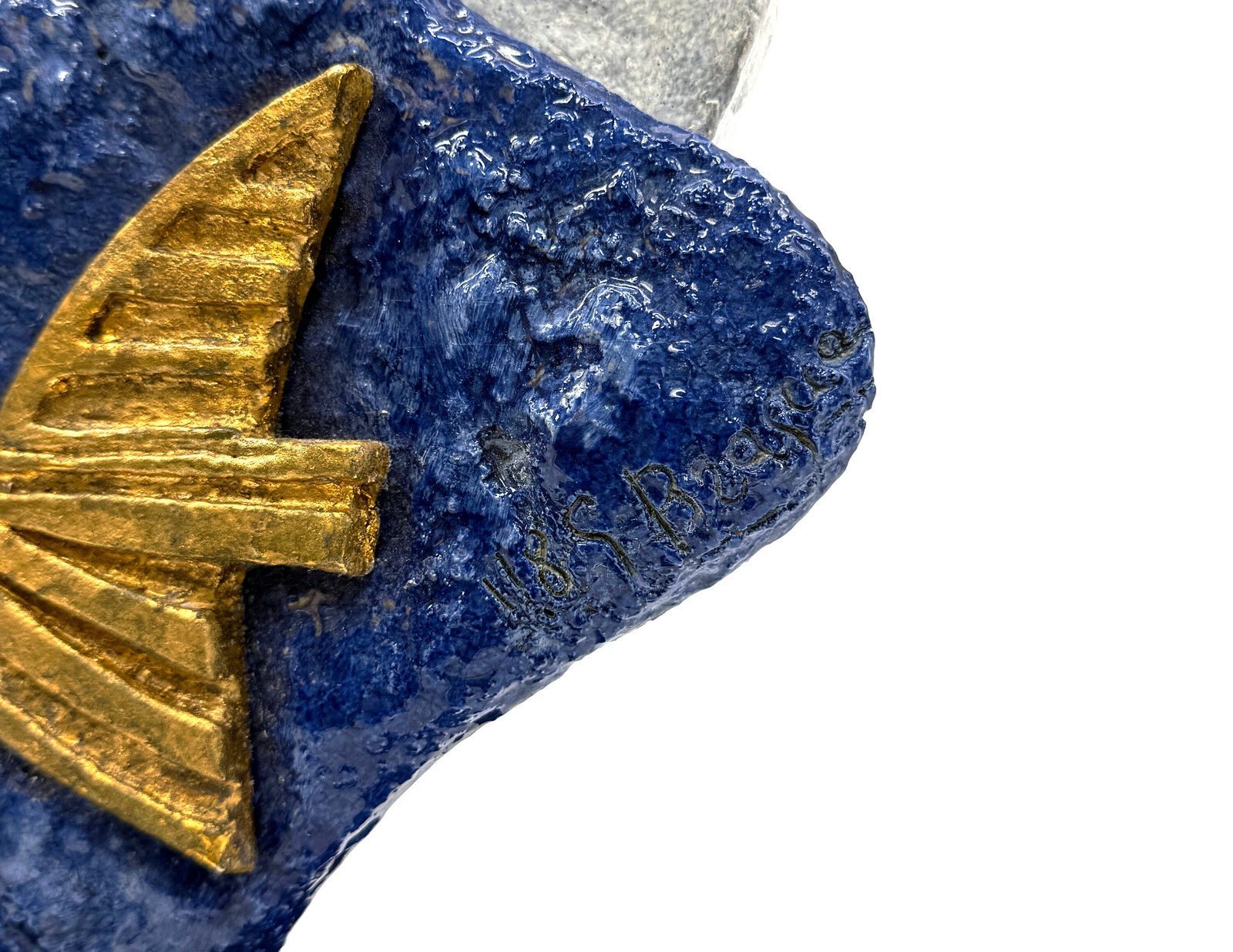 A sculptural composition featuring two stylized golden fish against a layered blue and white stone base.