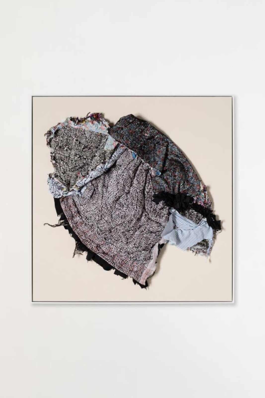 A person stands in a gallery space looking up at a framed textile artwork.