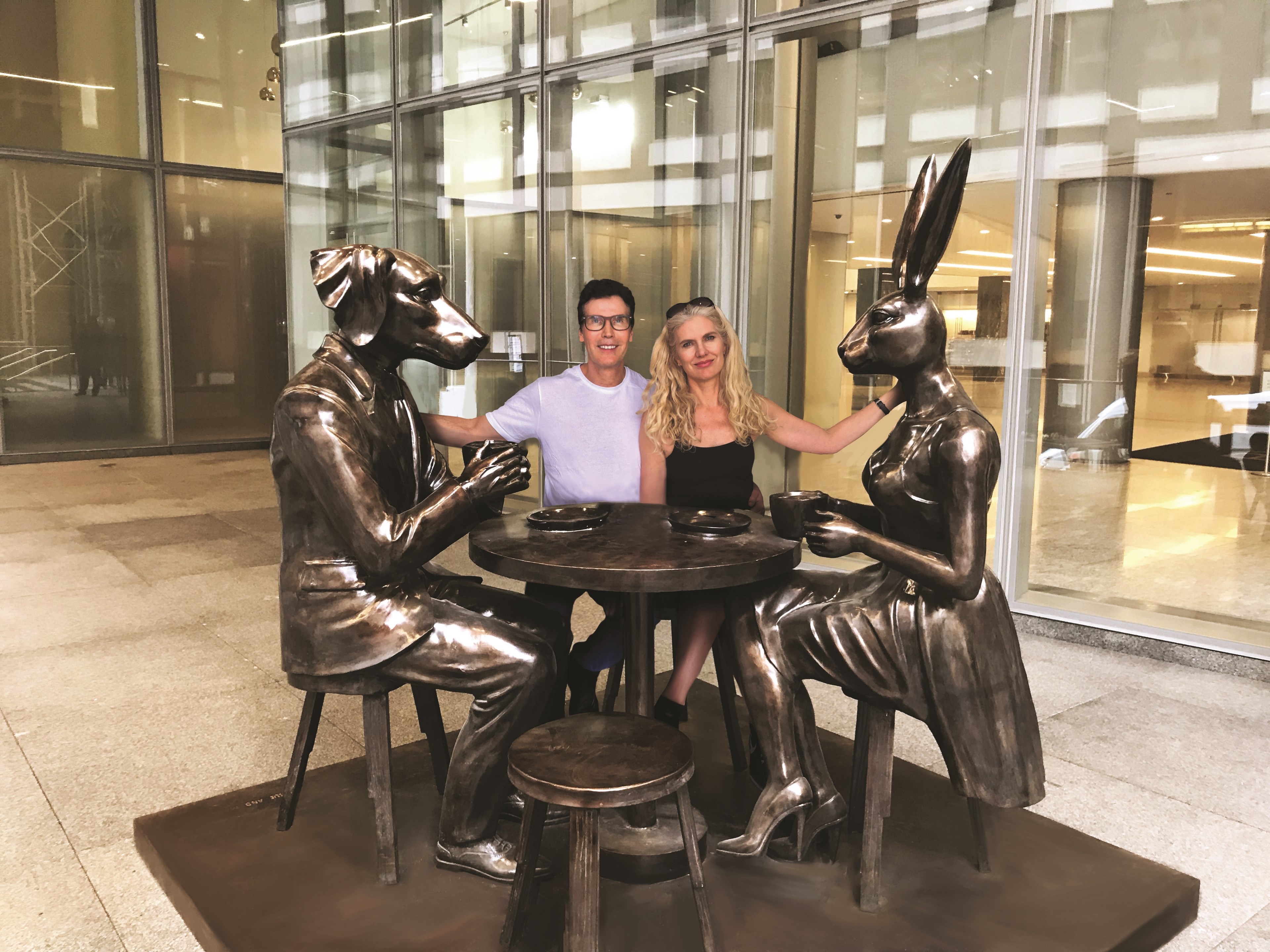 A man and woman sitting at a table with a statue of a dog and a rabbit.