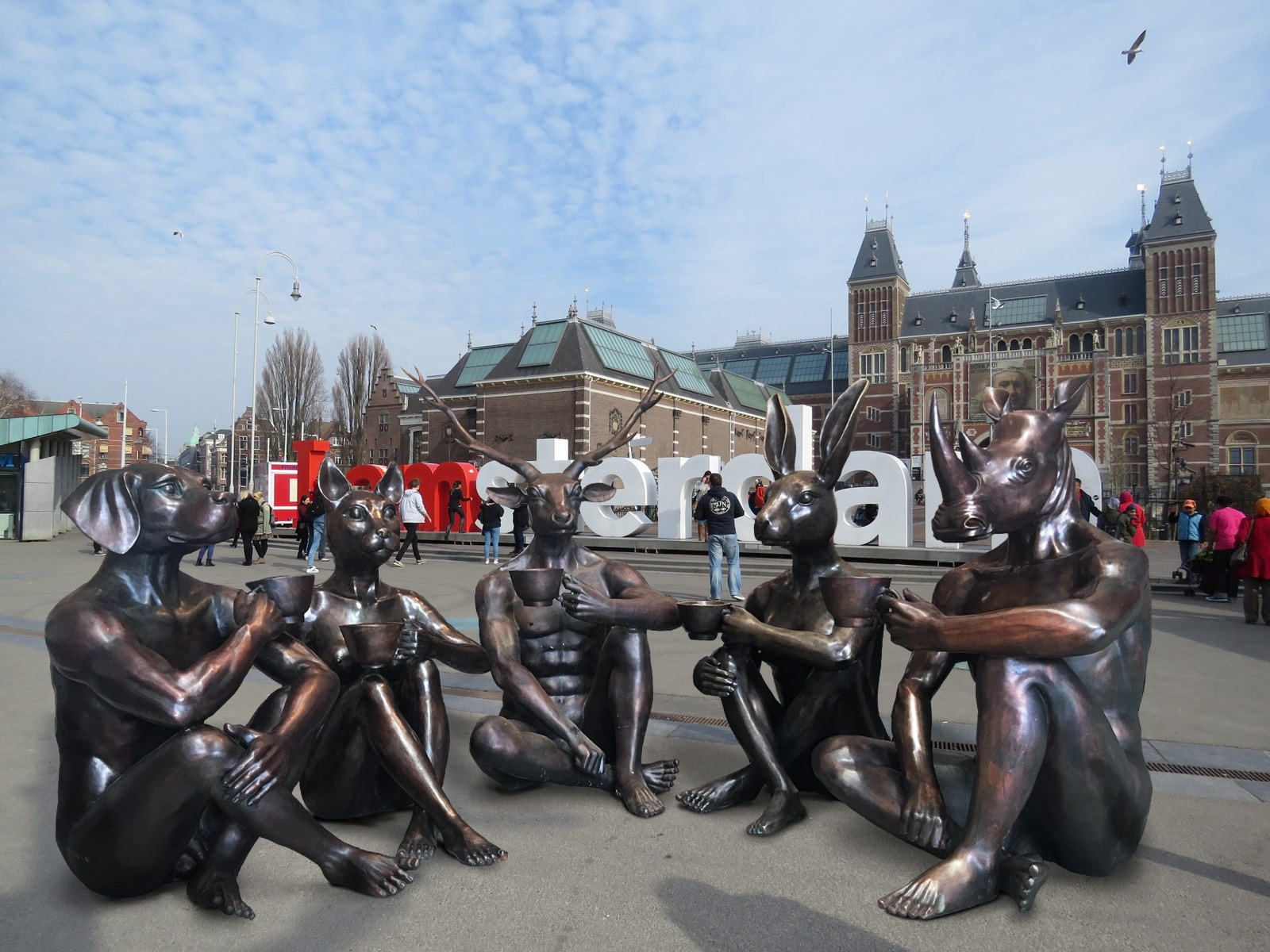 A group of bronze statues sitting on the ground in front of a building.