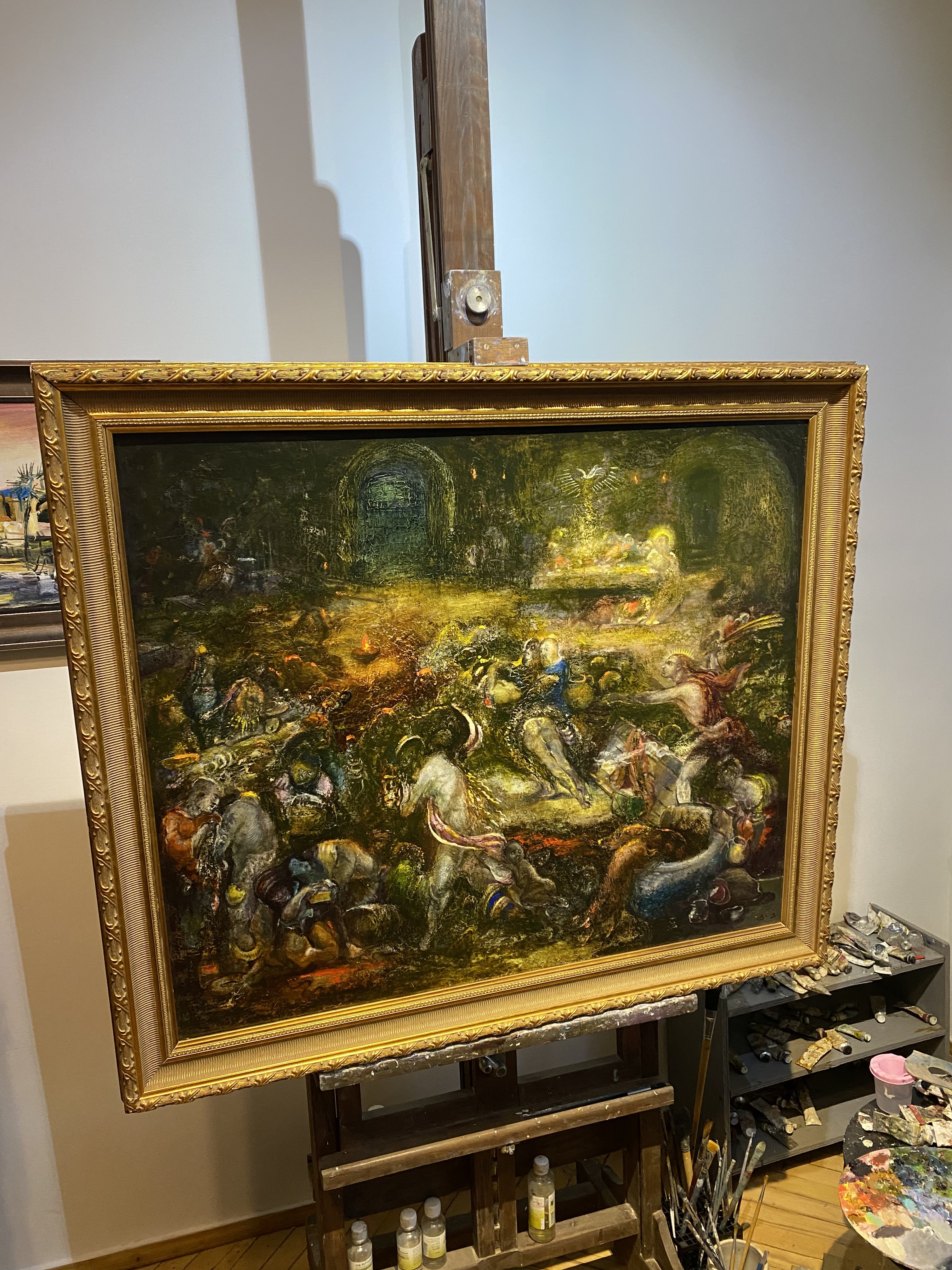 A painting on a easel in a room with a painting on the wall.