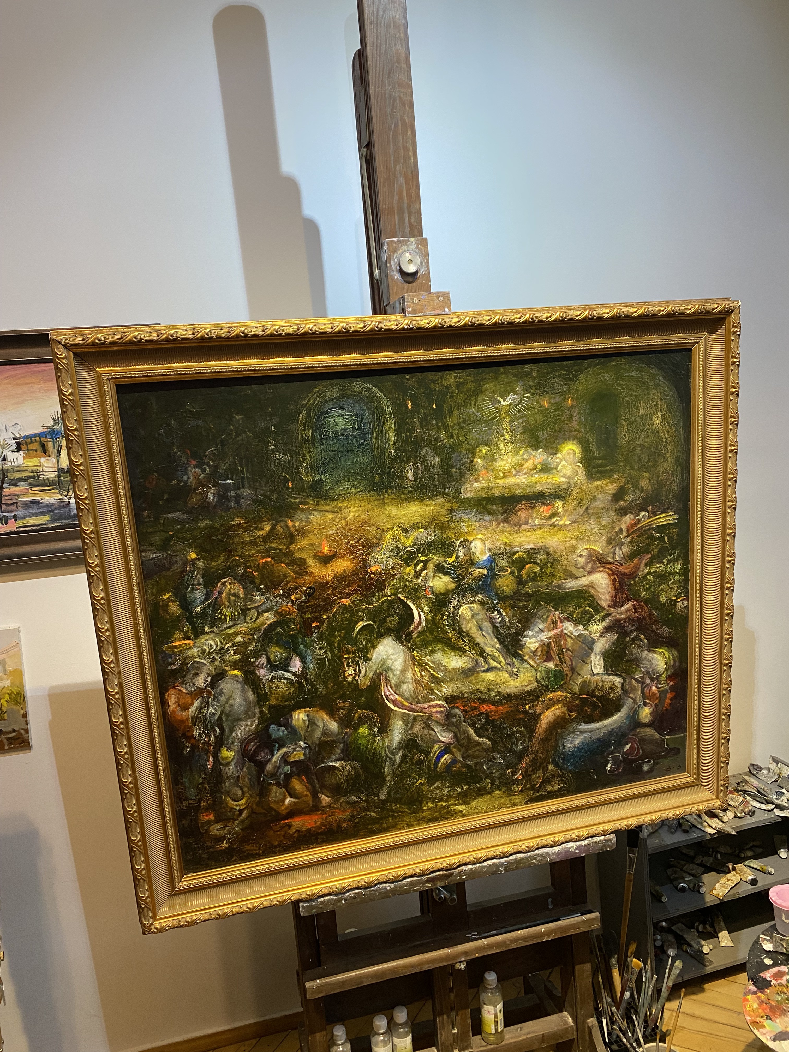 A painting on a easel in a room with a painting on the wall.
