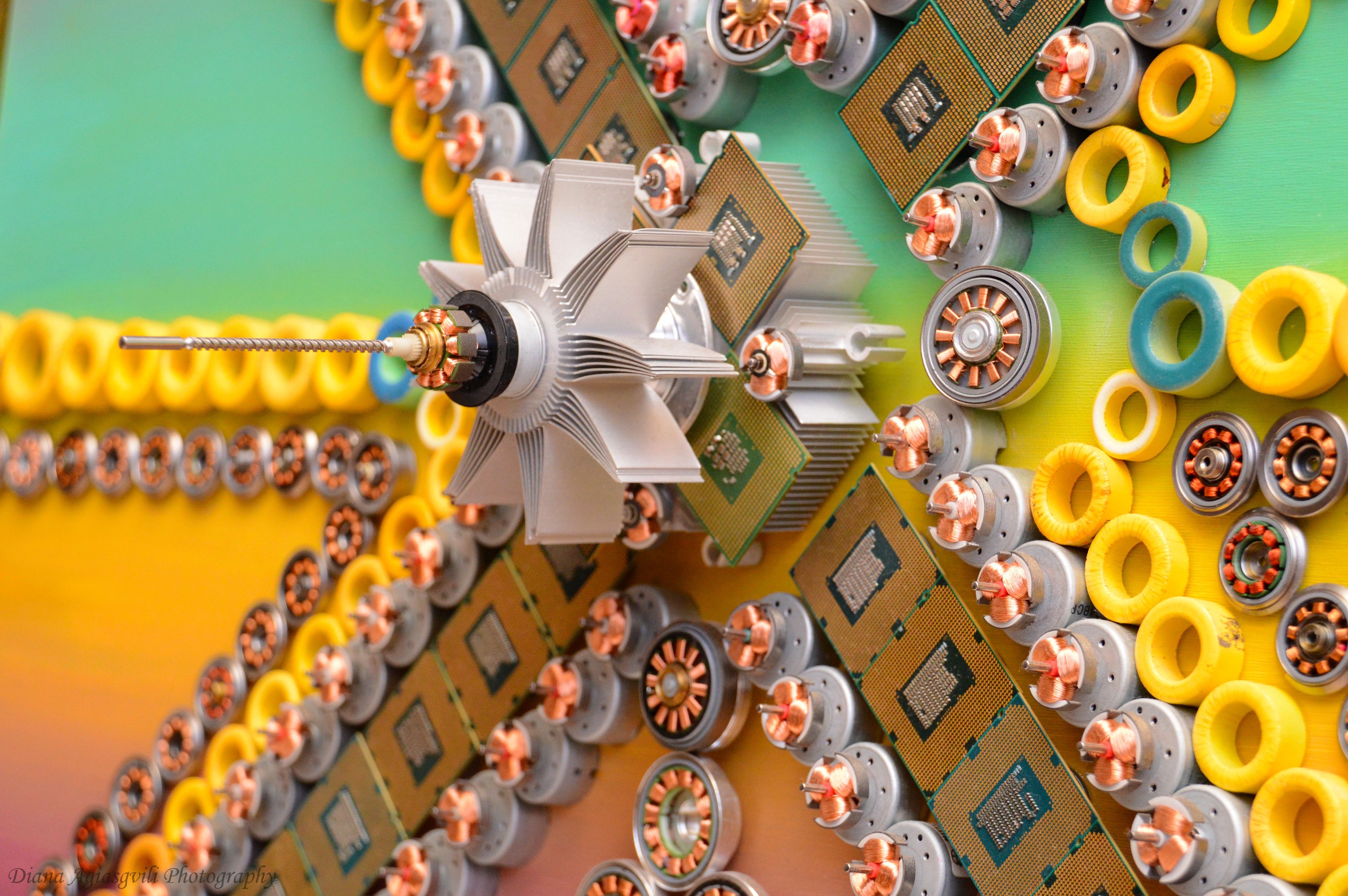 A macro photograph of a metallic gear surrounded by yellow rings and green circuit boards.