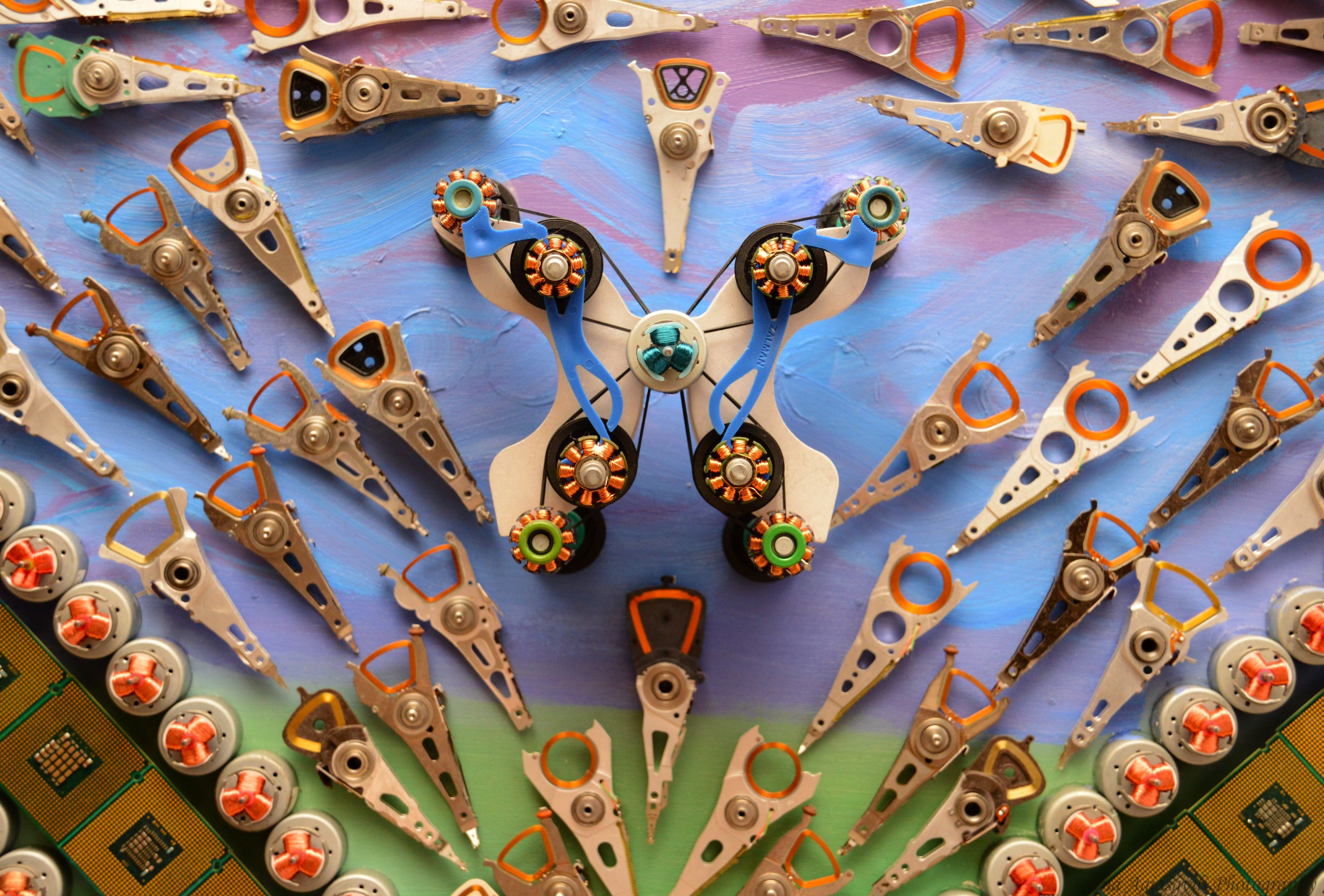 A macro photograph of a metallic gear surrounded by yellow rings and green circuit boards.