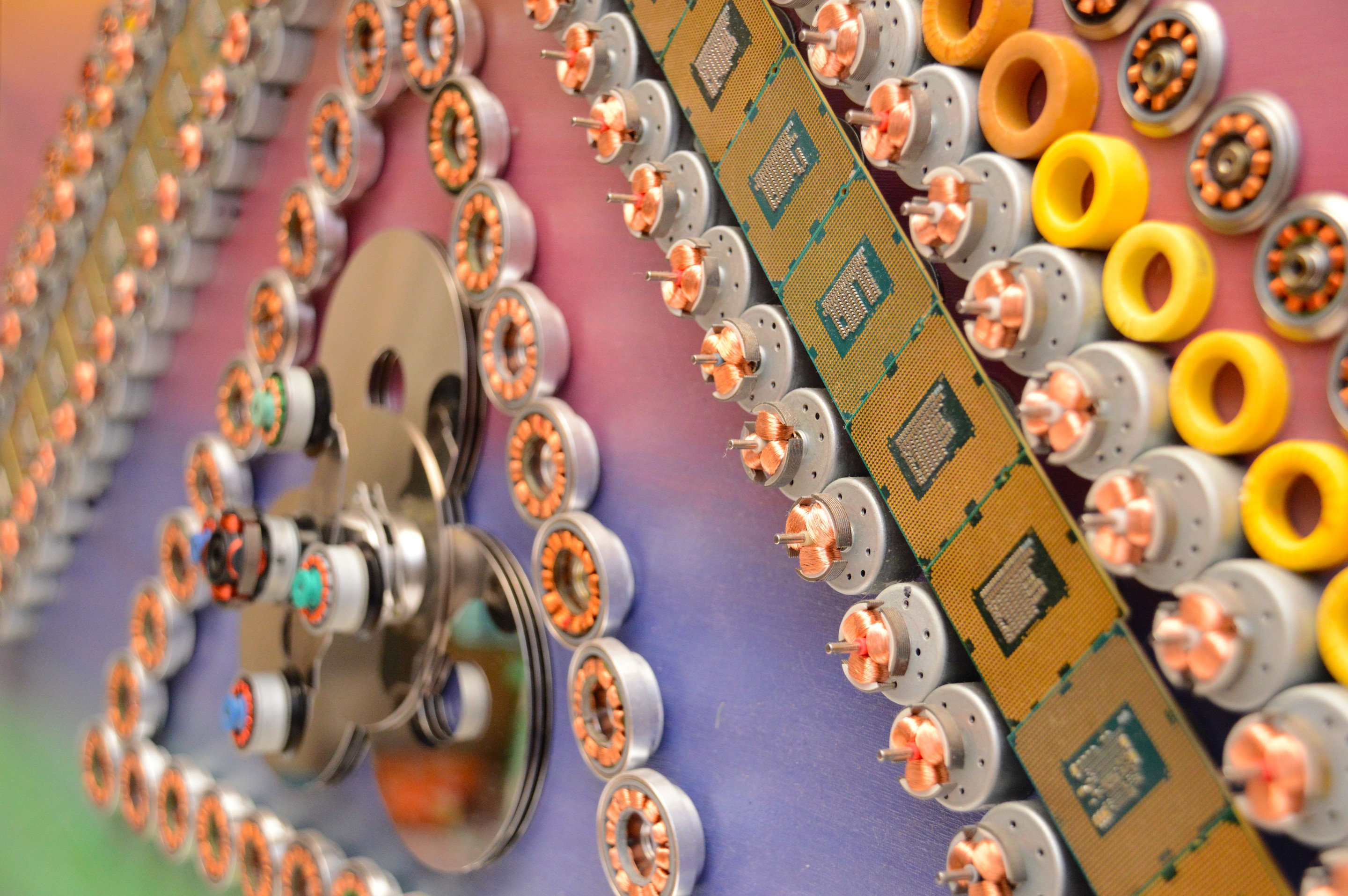 A macro photograph of a metallic gear surrounded by yellow rings and green circuit boards.