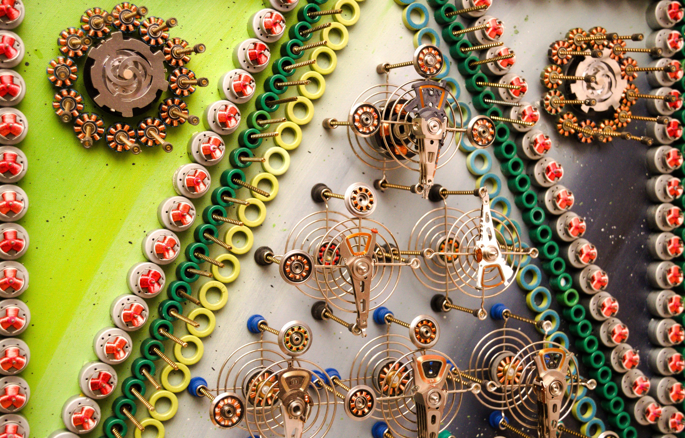 A mechanical collage featuring a grid of metallic figures surrounded by coiled springs and small gears.