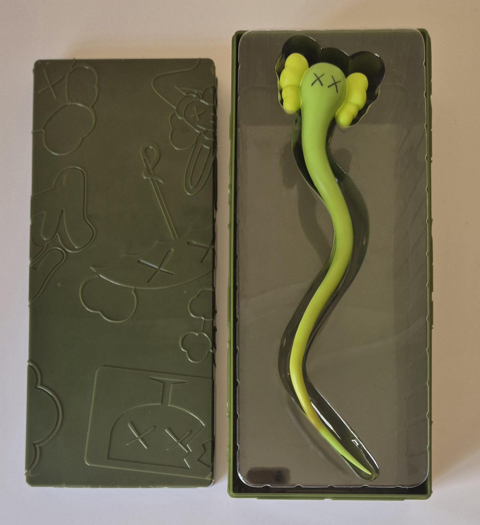 A green snake in a clear plastic box on a wall.