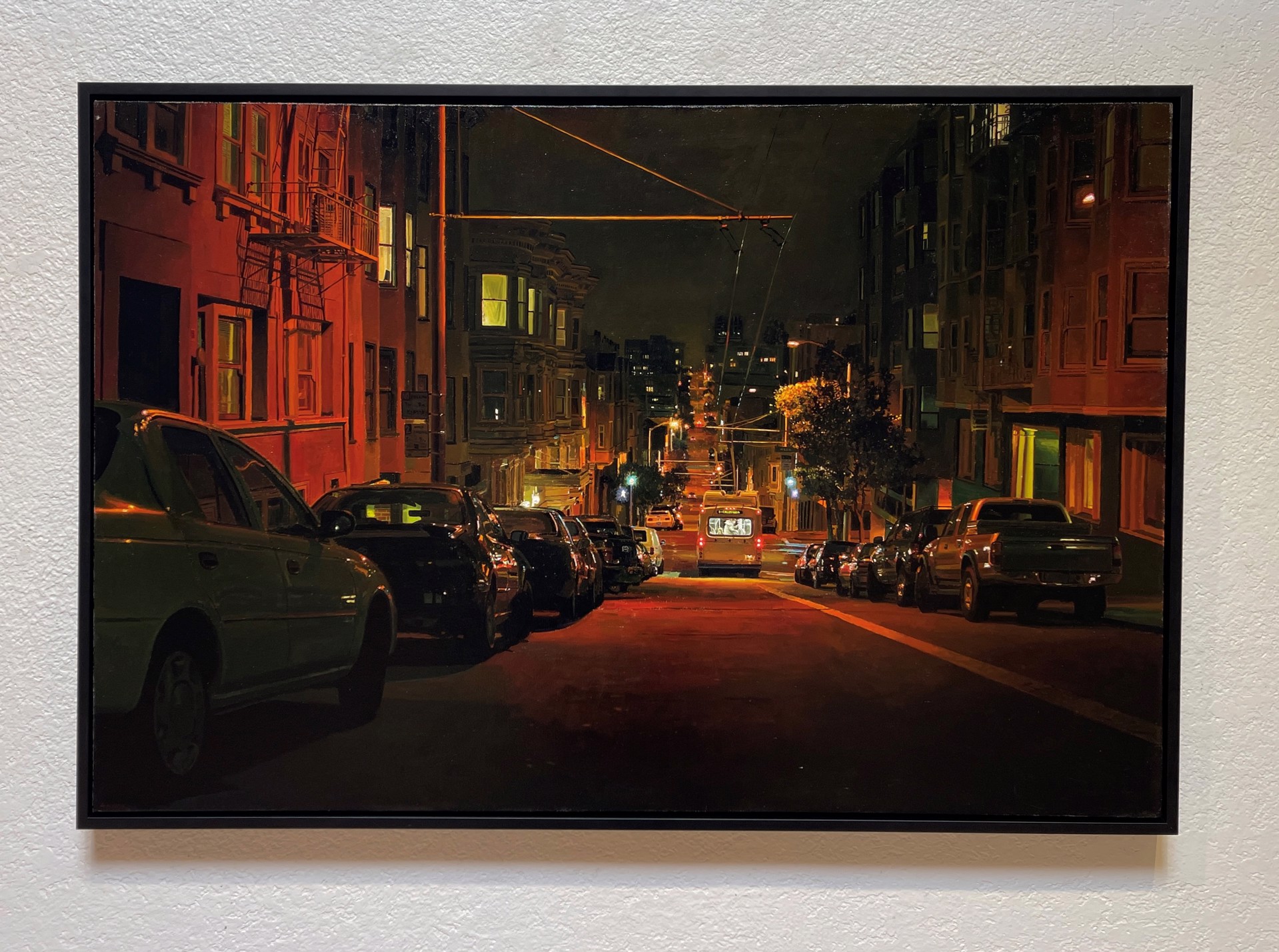 A painting of a city street at night with cars parked on the side of the road.