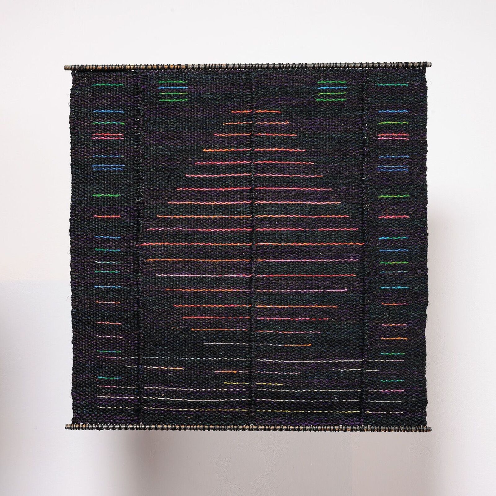 A woven textile featuring a central geometric pattern of horizontal lines against a dark background.