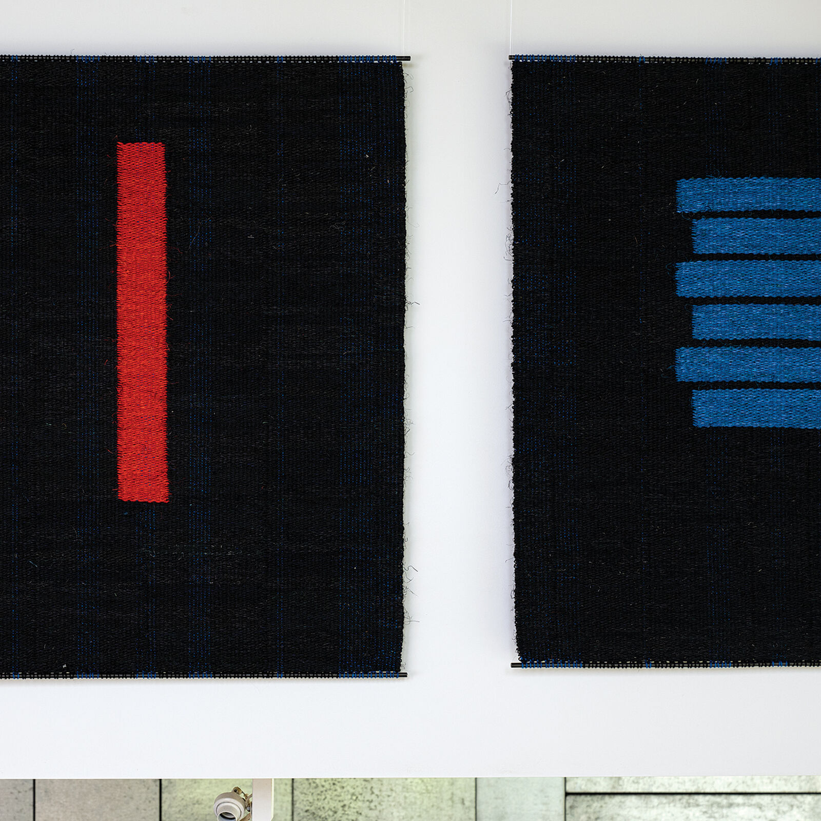 A woven textile featuring a bold red vertical stripe against a dark textured background.