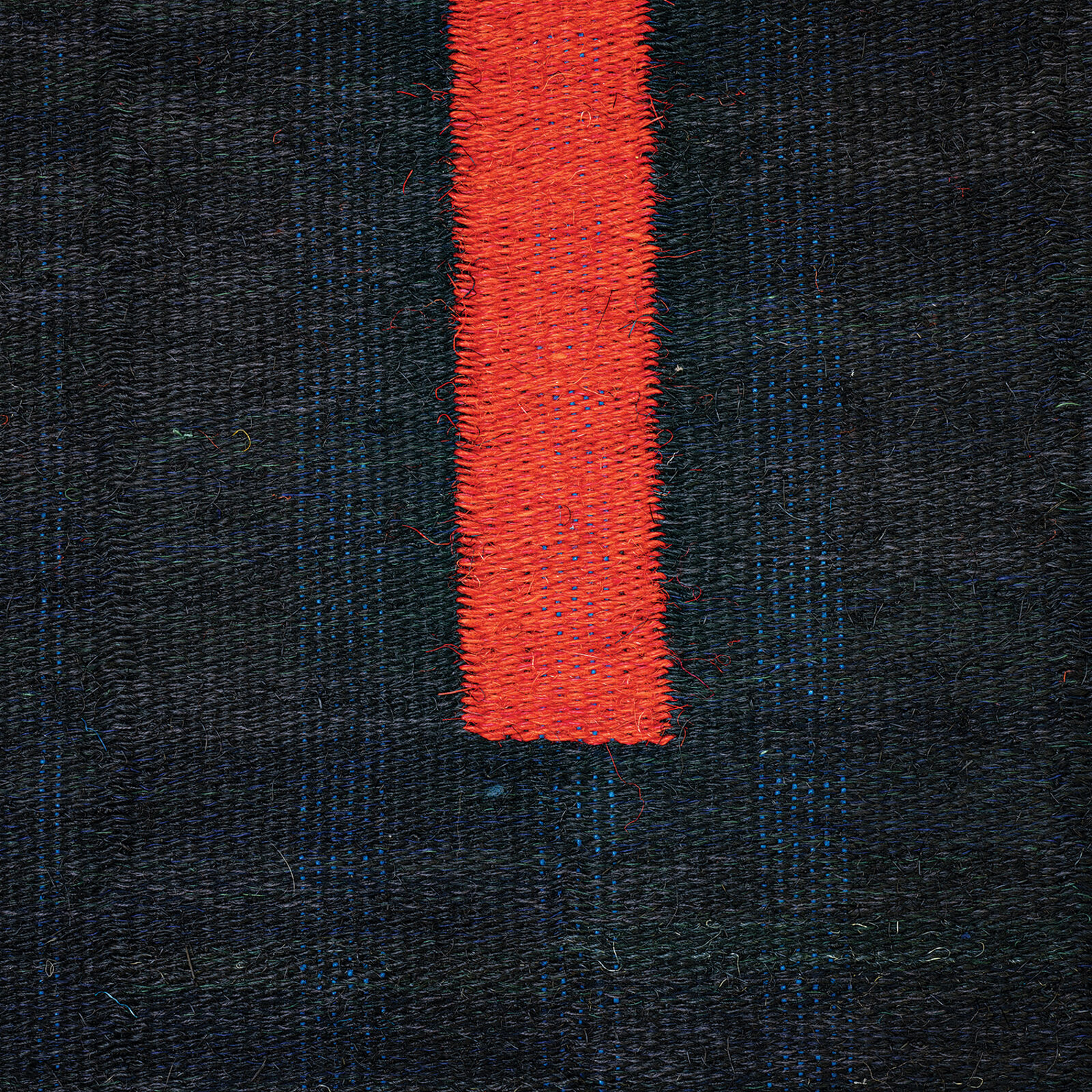 A woven textile featuring a bold red vertical stripe against a dark textured background.