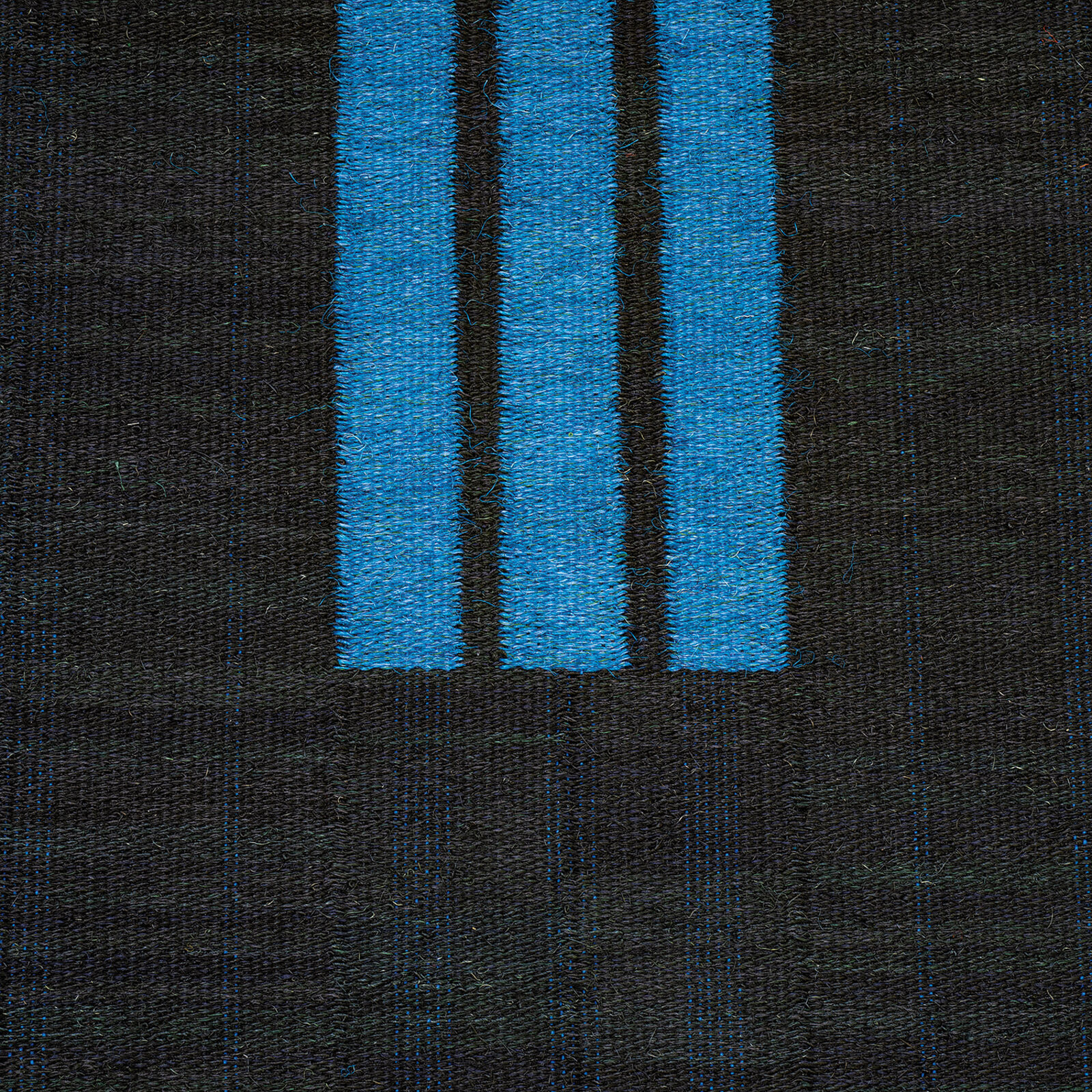 A woven textile featuring three vertical blue stripes against a dark, textured background.