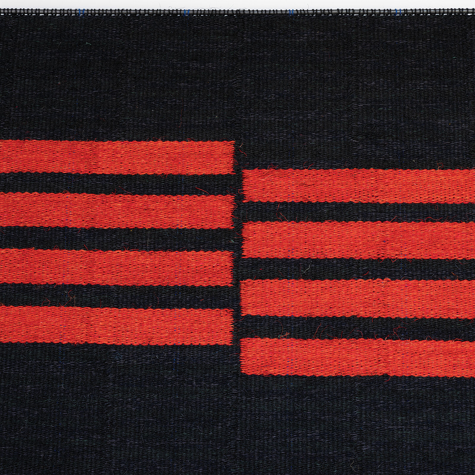 A minimalist textile piece featuring bold red horizontal stripes on a black woven background.