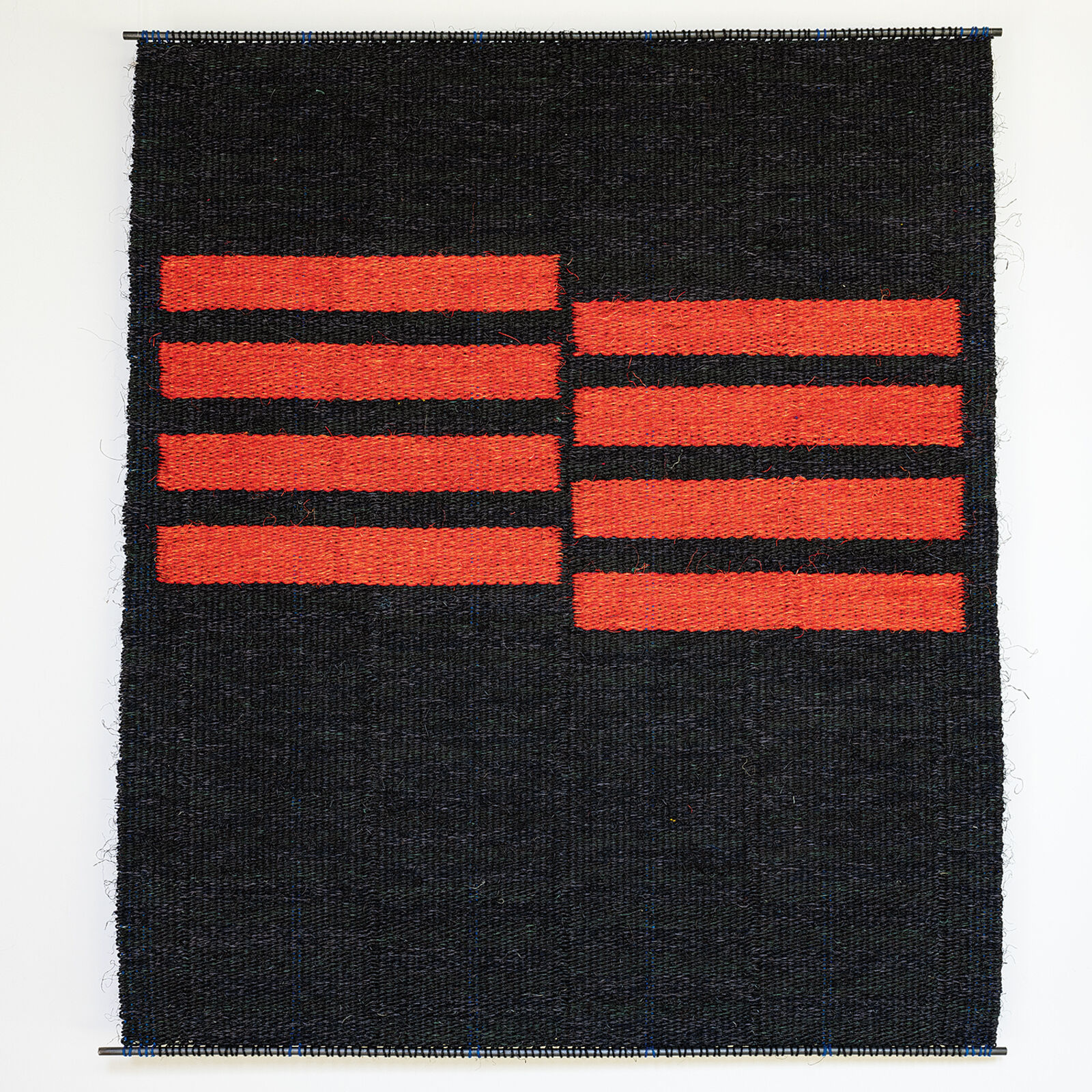 A minimalist textile piece featuring bold red horizontal stripes on a black woven background.