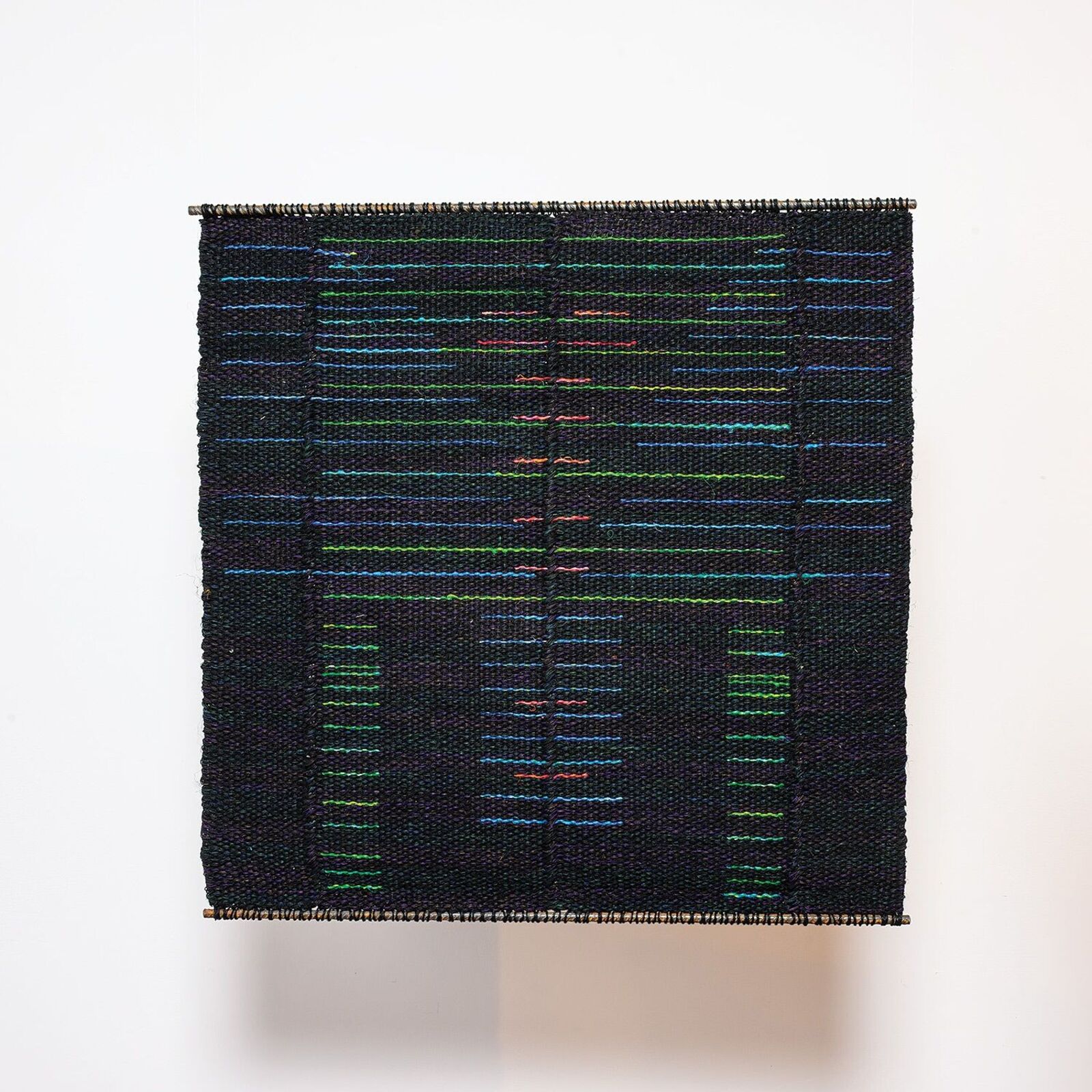 A woven textile featuring a dark background with colorful horizontal lines forming an abstract figure.