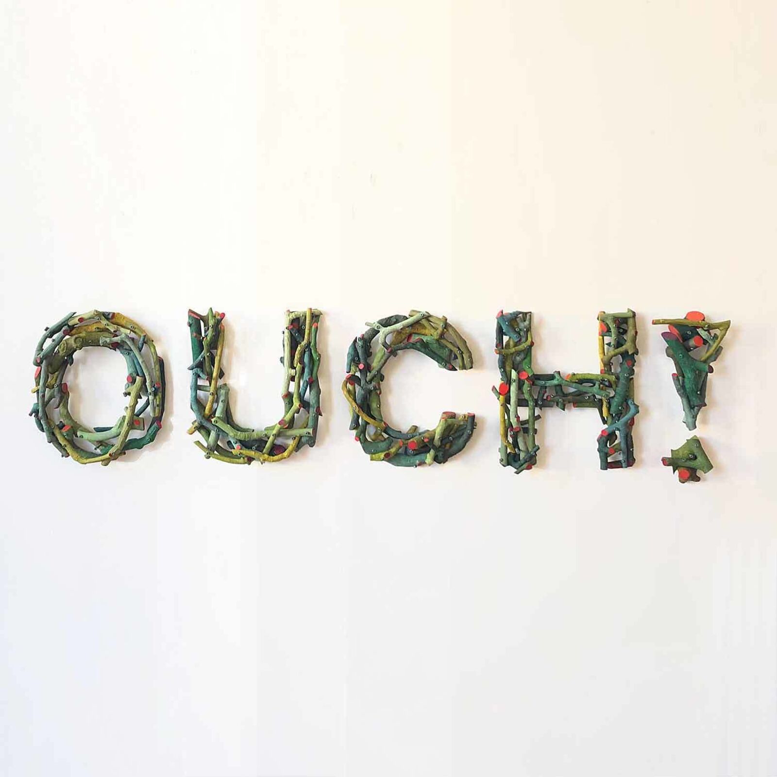 A sign that says Ouch! on a white wall. 