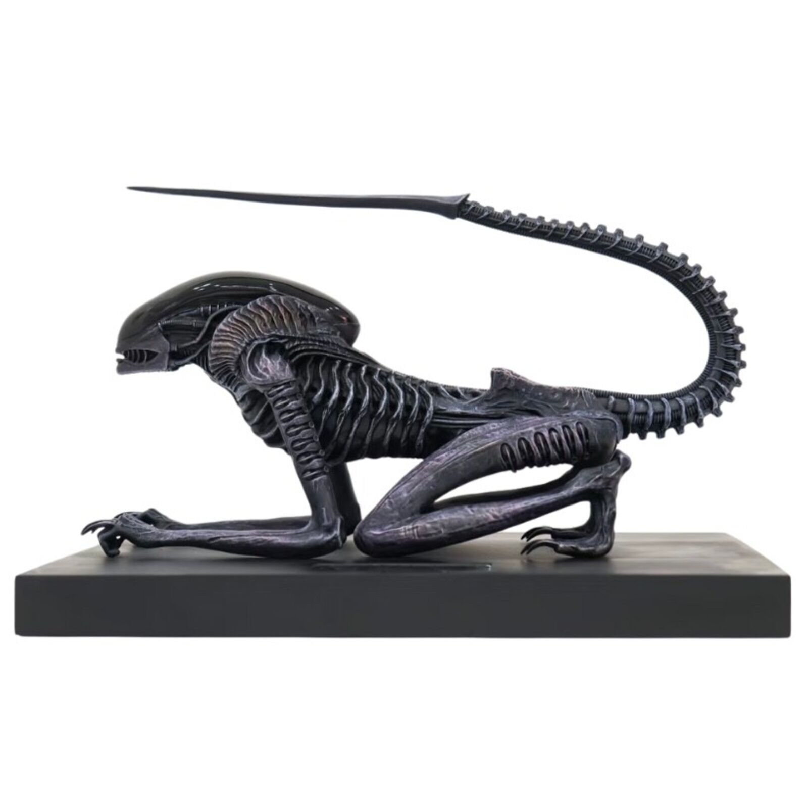 A statue of an alien with a long tail on a black base.