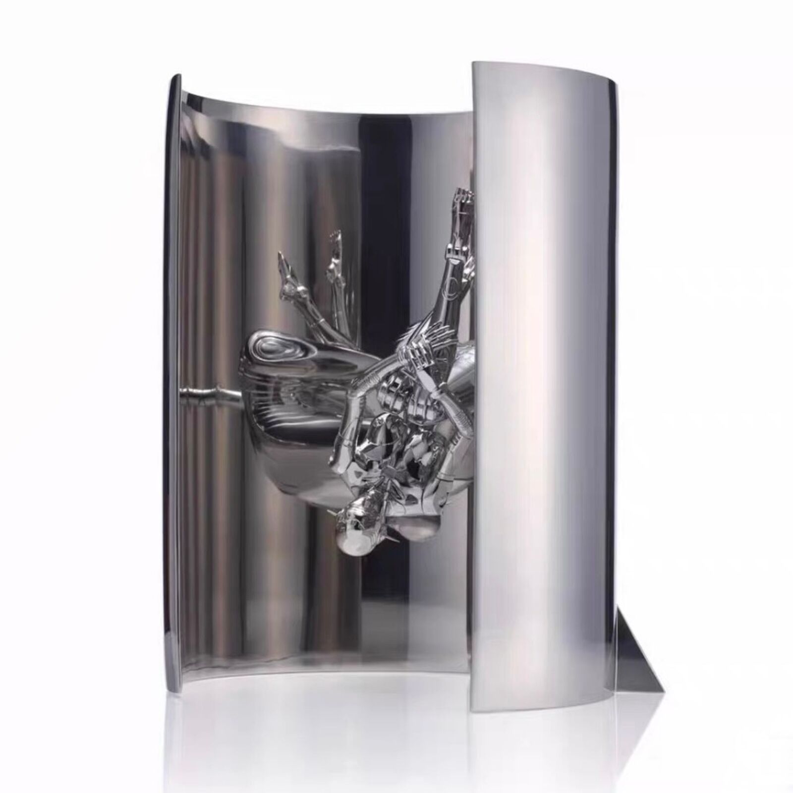 A silver sculpture of a man sitting on top of a toilet.