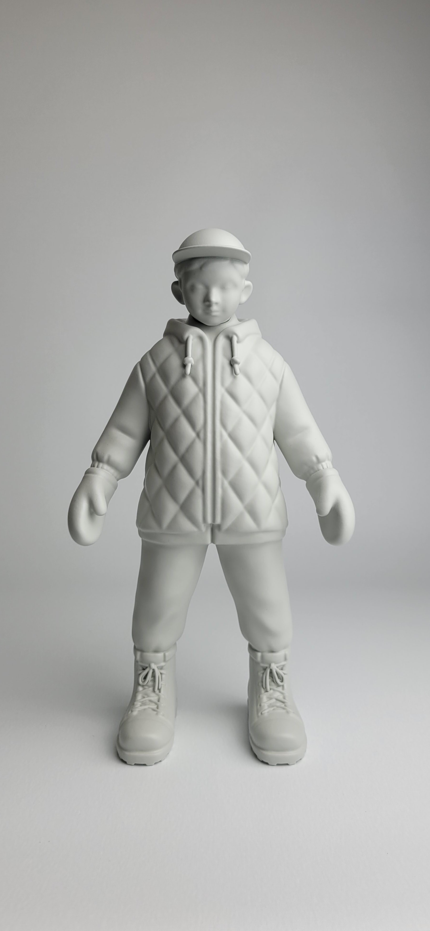 A monochromatic sculpture of a figure in winter gear standing against a neutral background.