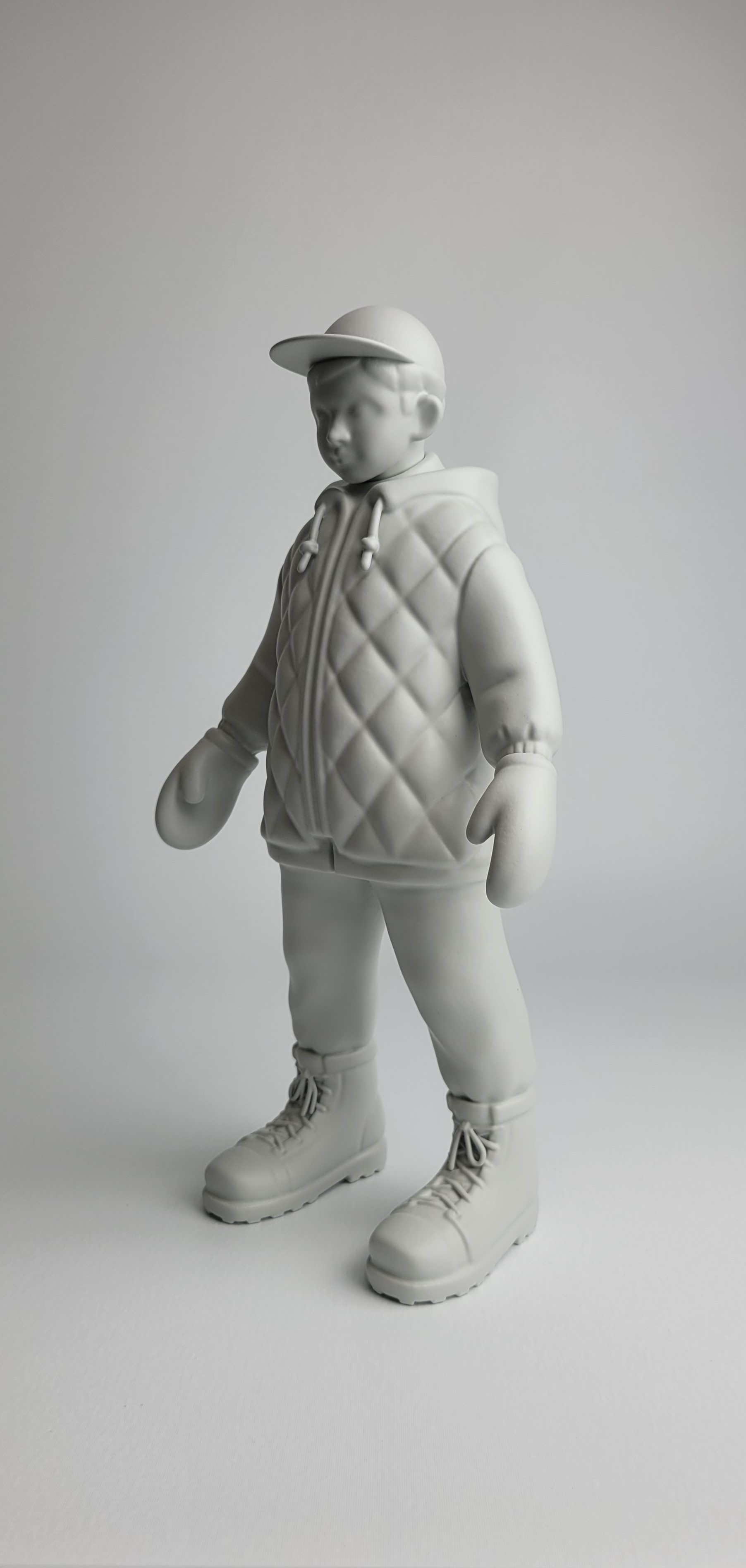 A monochromatic sculpture of a figure in winter gear standing against a neutral background.