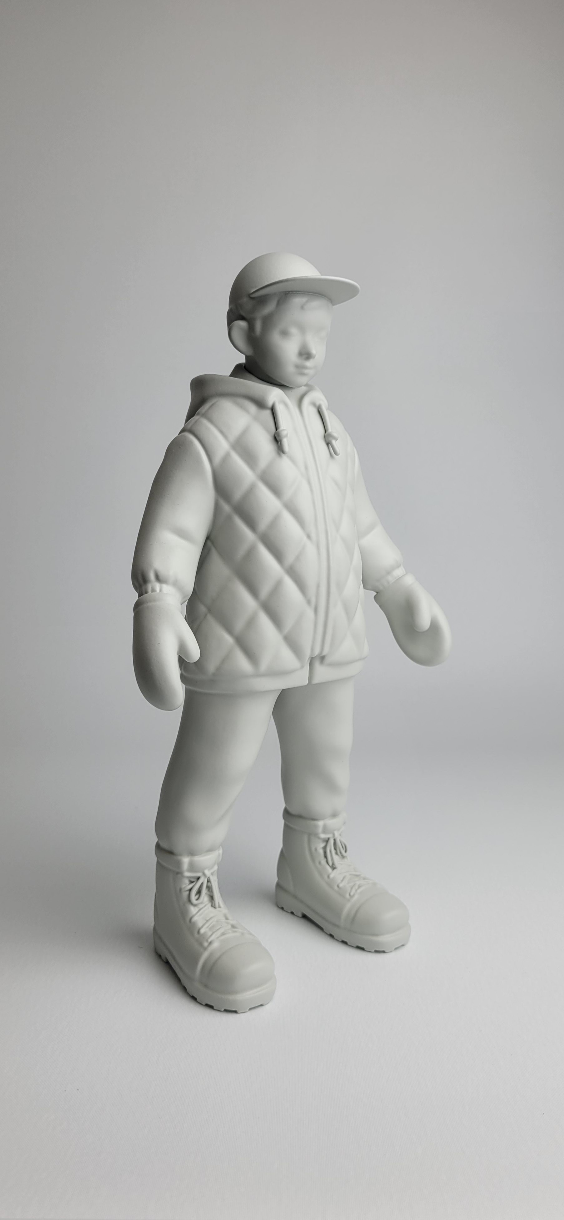 A monochromatic sculpture of a figure in winter gear standing against a neutral background.