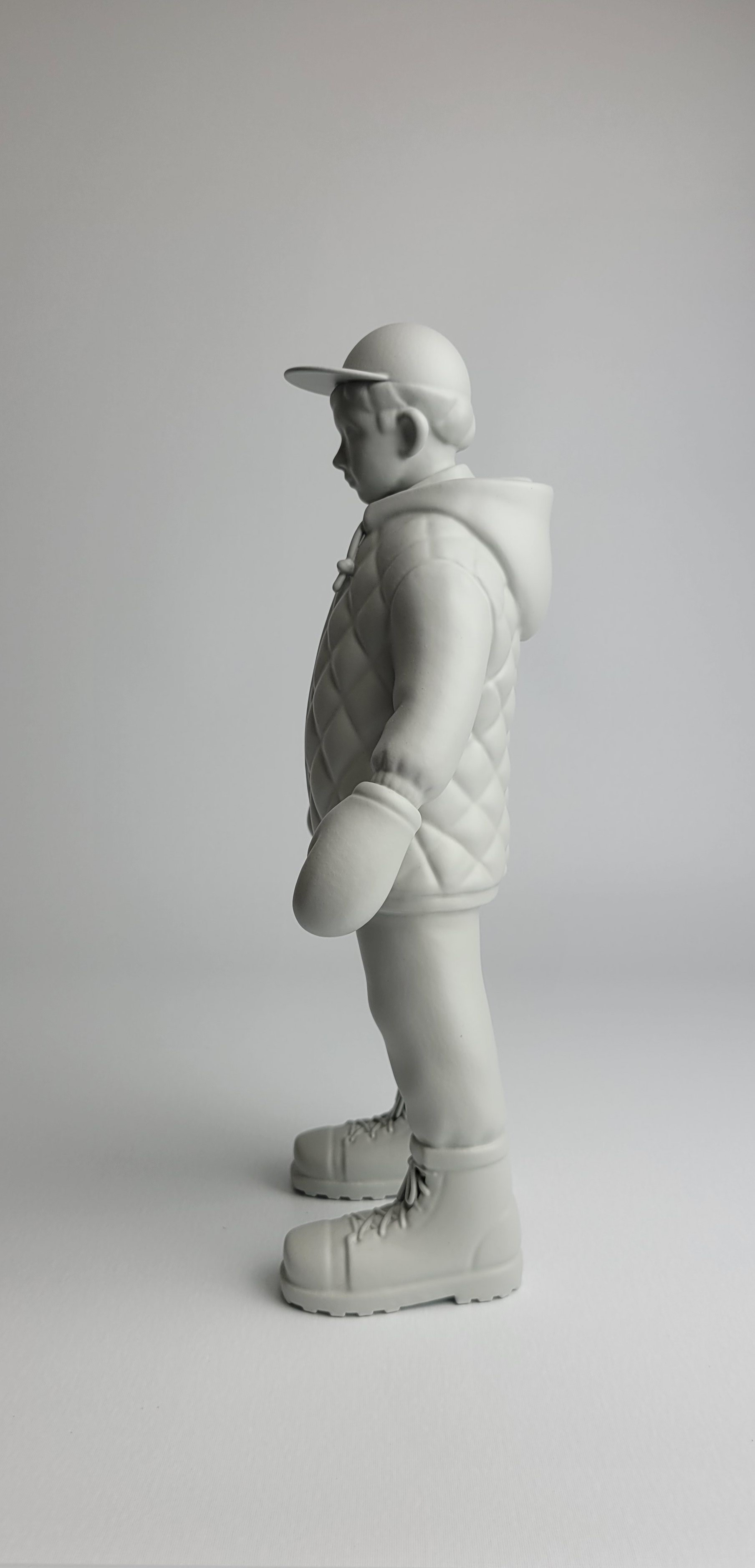 A monochromatic sculpture of a figure in winter gear standing against a neutral background.