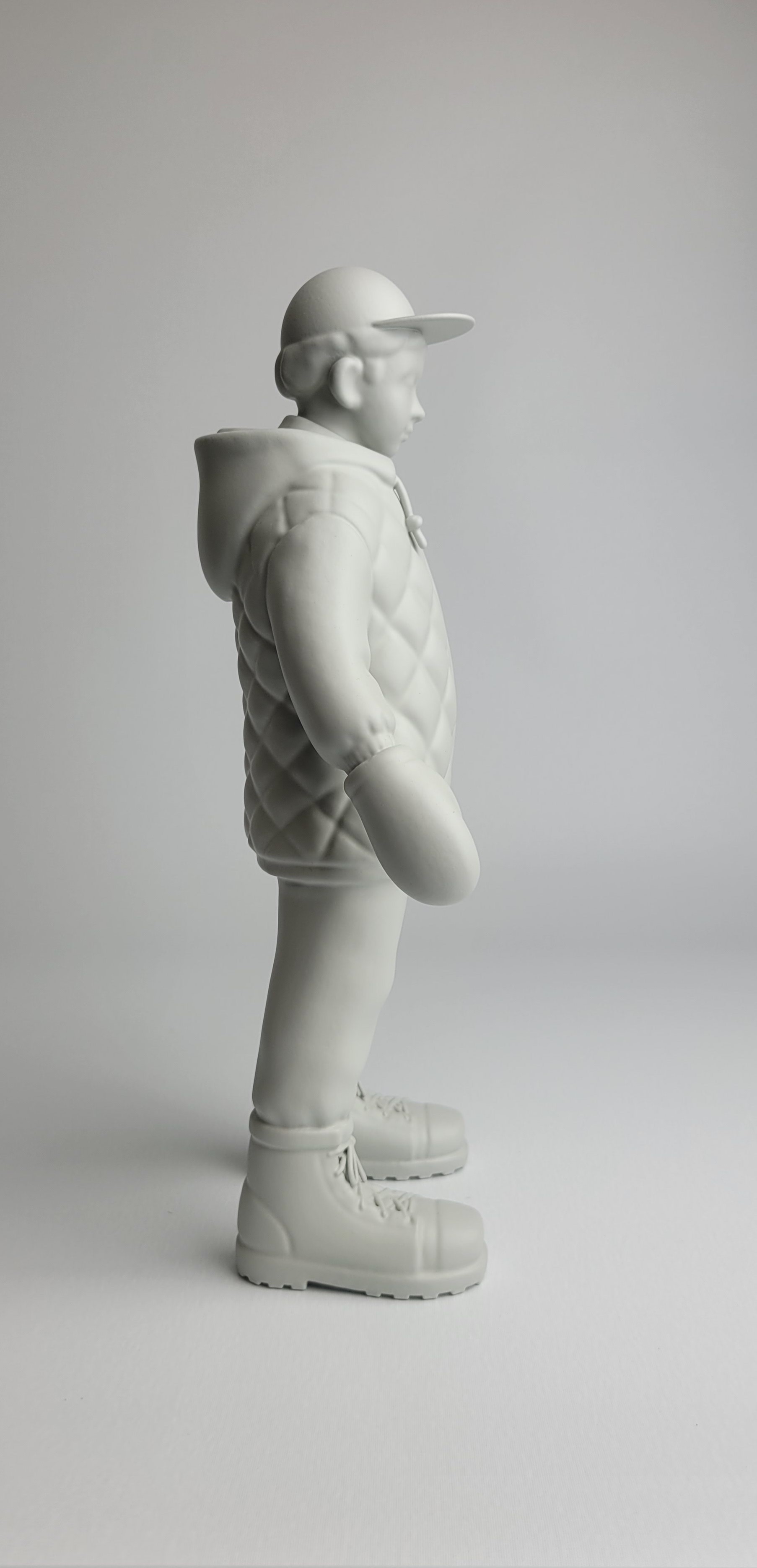 A monochromatic sculpture of a figure in winter gear standing against a neutral background.